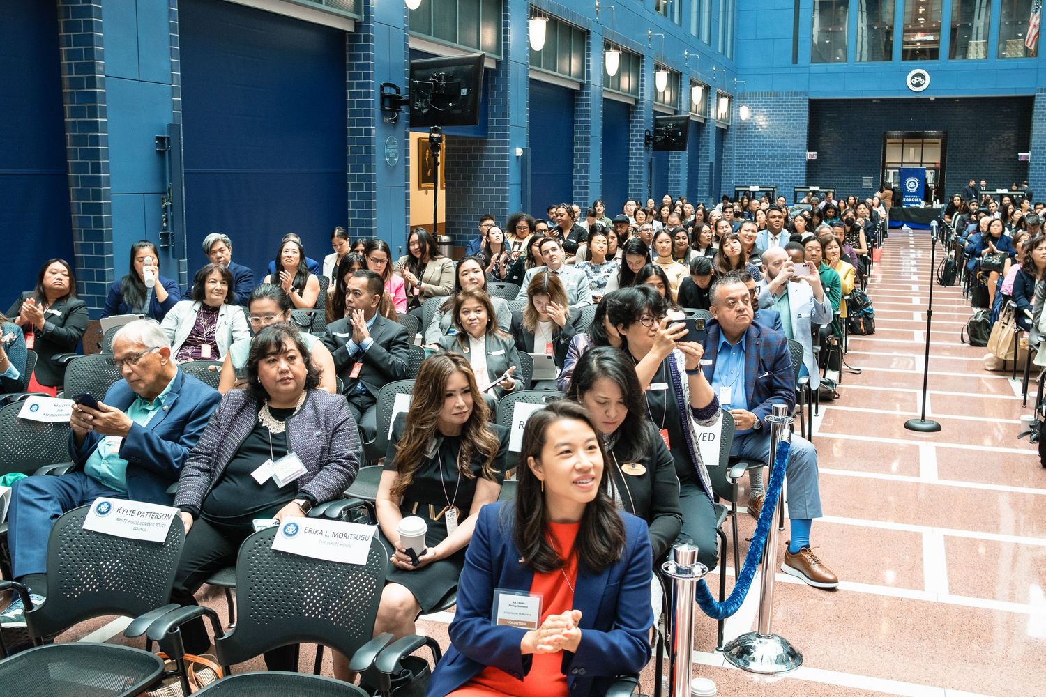 Large audience of diverse attendees seated at a professional conference or summit in a modern venue.