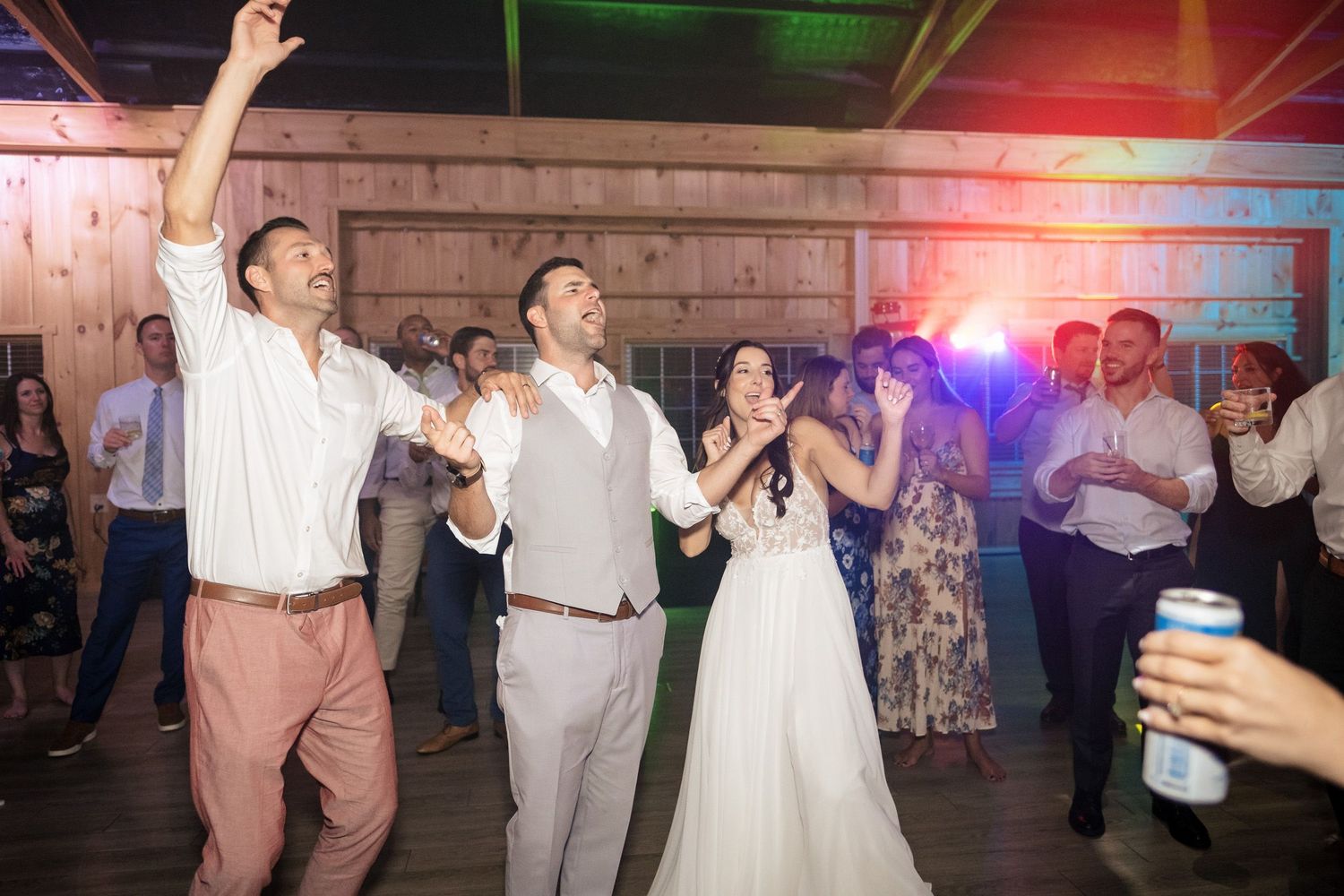 Joyful bride and groom celebrating with raised arms on the dance floor at wedding reception.