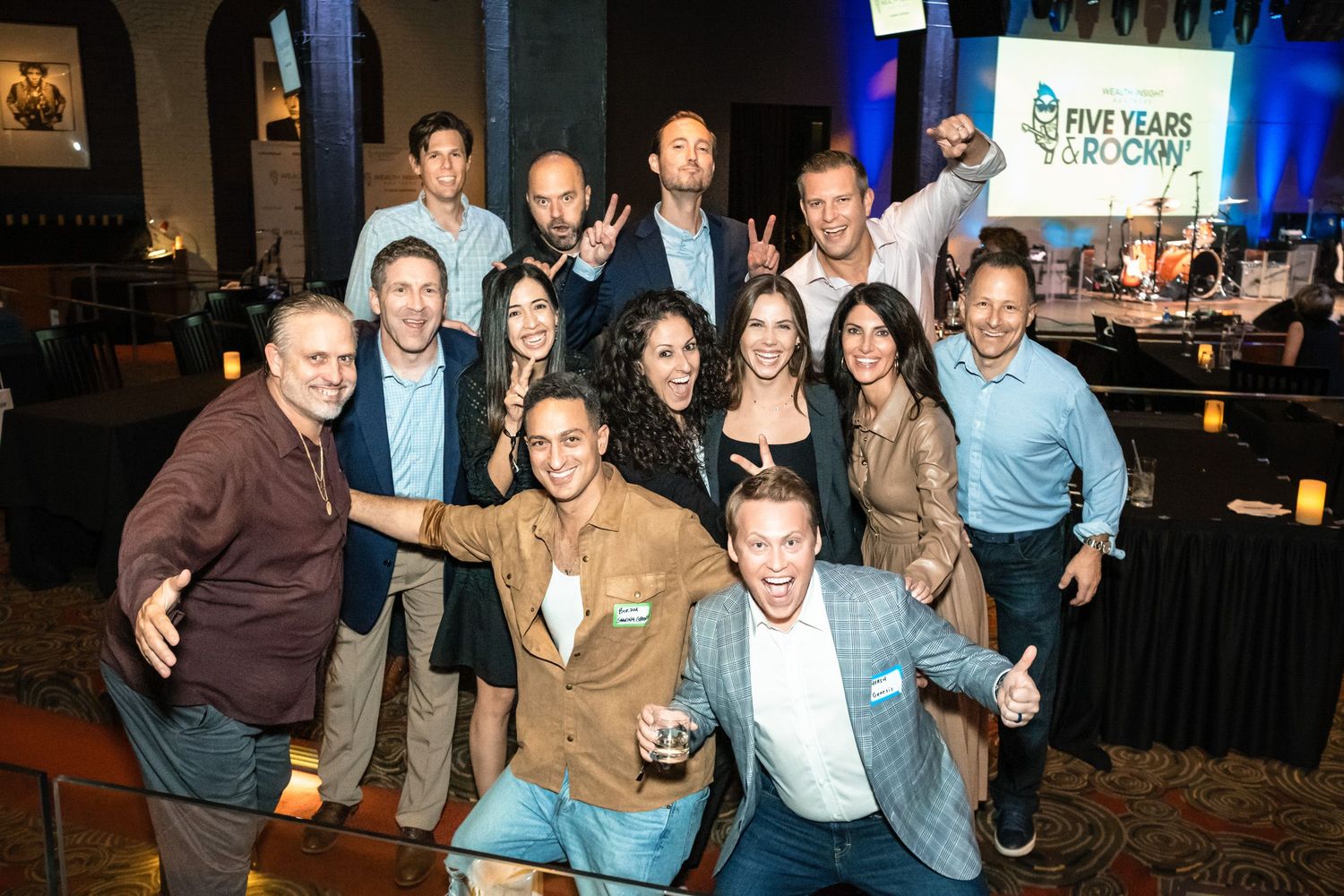 Group of smiling professionals celebrating a five-year anniversary event at a corporate party venue.