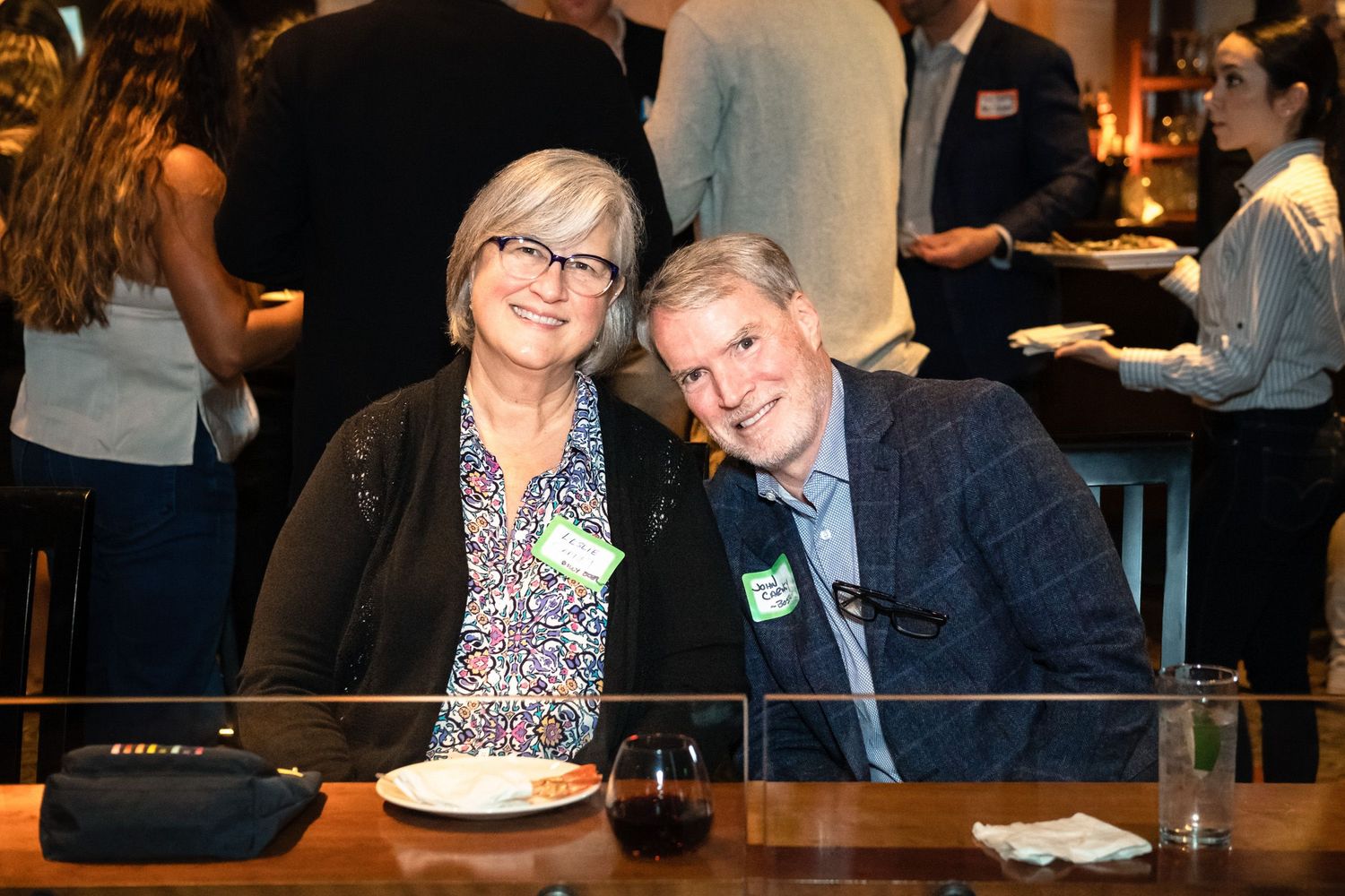 A smiling couple wearing name tags sit together at a restaurant networking event.