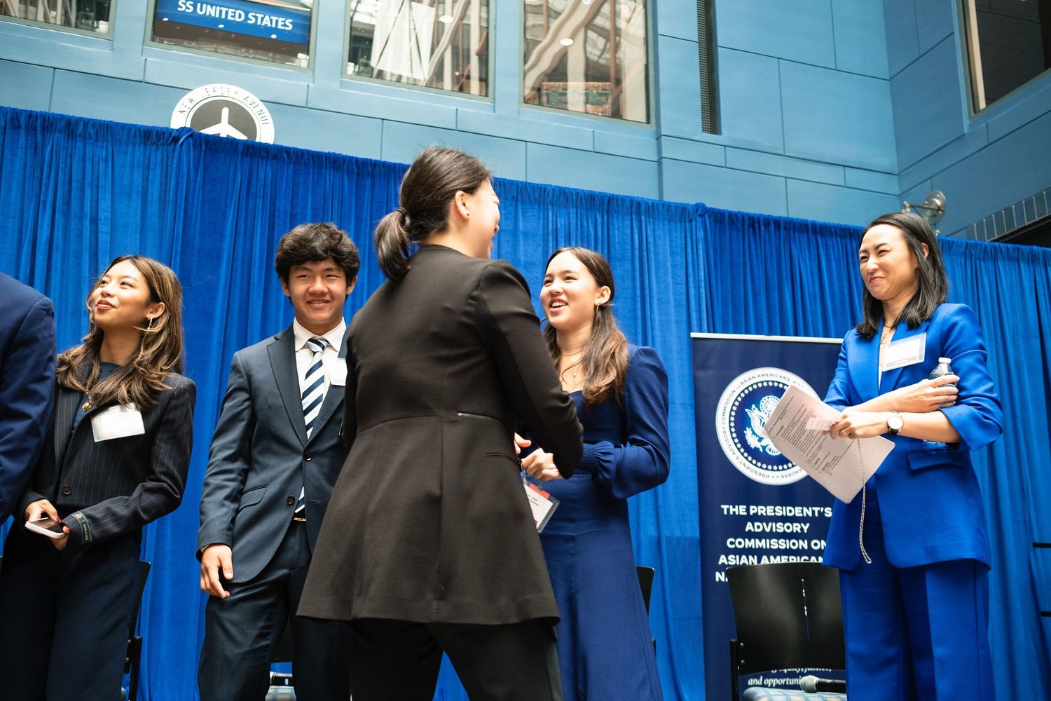 Group of professionals networking and shaking hands at an official advisory commission event.