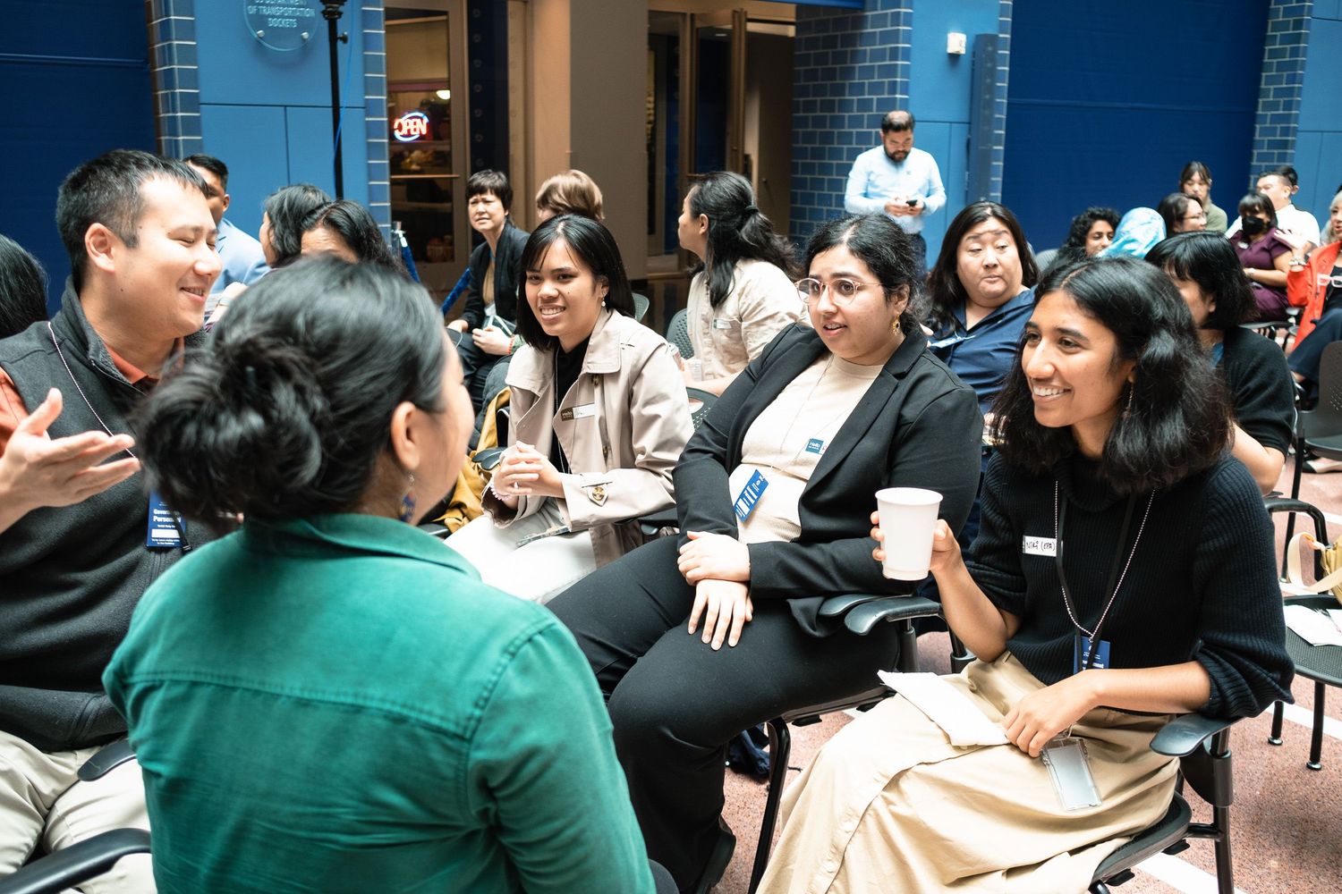 Diverse group of young professionals networking and conversing at an indoor social event.