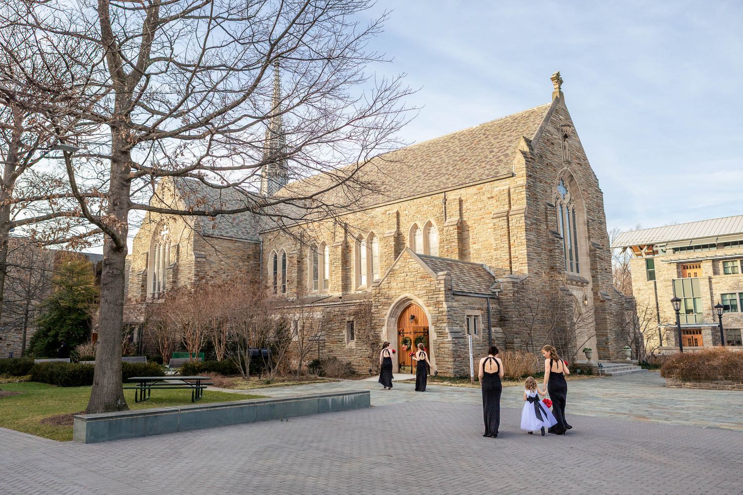 Wedding party poses outside a historic stone church during a winter wedding ceremony.