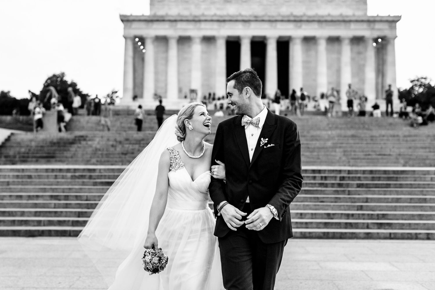 Black and white photo of a bride and groom sharing a romantic moment in front of the Lincoln Memorial in Washington DC.