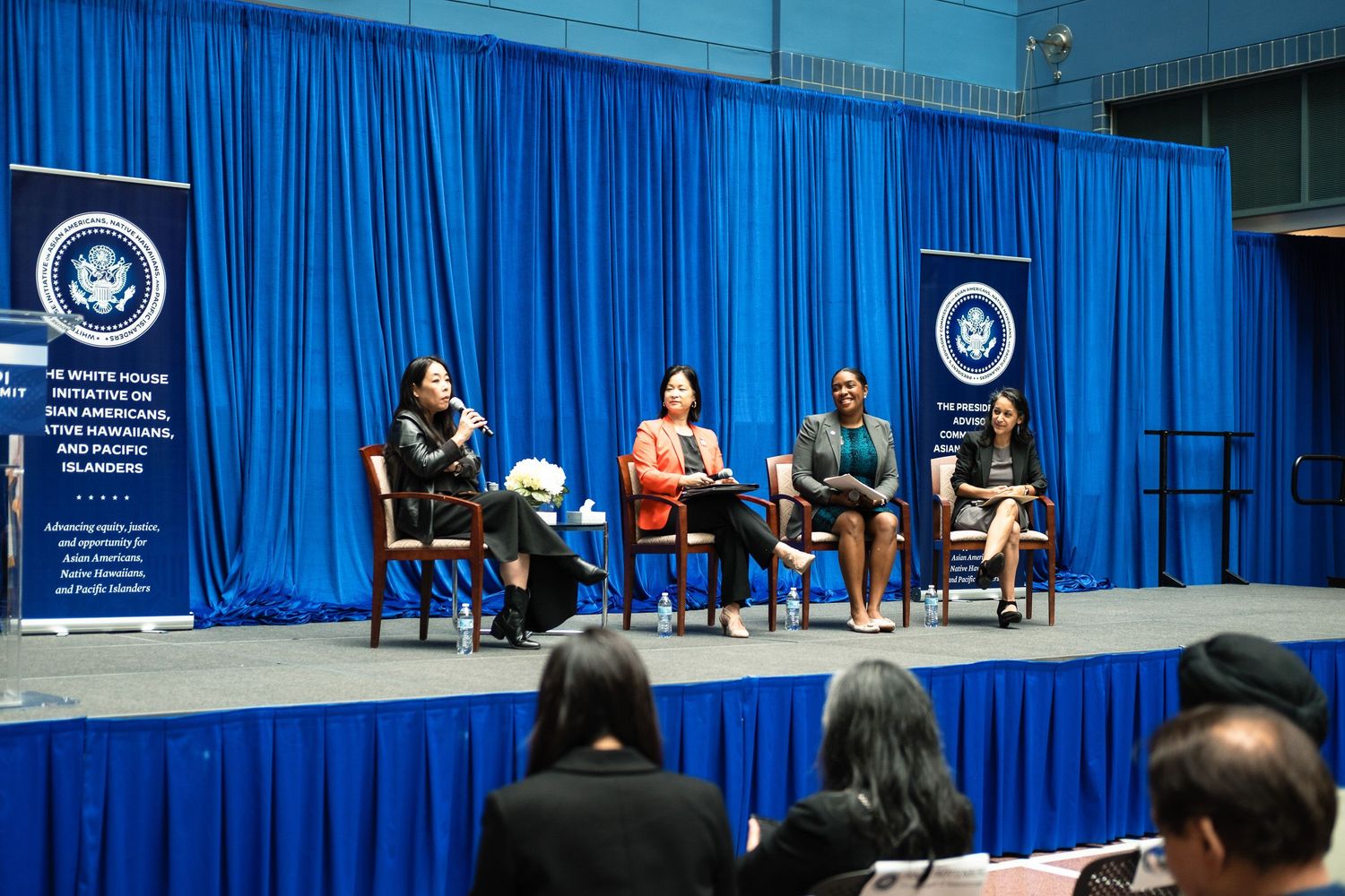 Four women panelists speak on stage at a White House Initiative on Asian Americans and Pacific Islanders event.