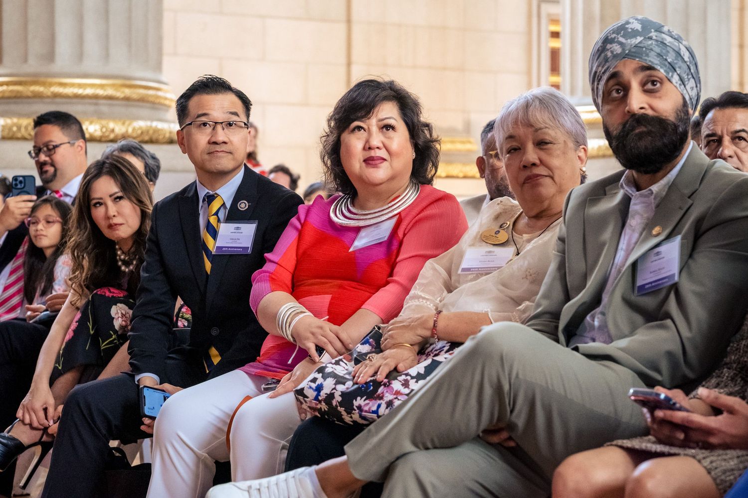 Diverse group of attendees seated at a formal event, including Asian and South Asian individuals wearing business attire.