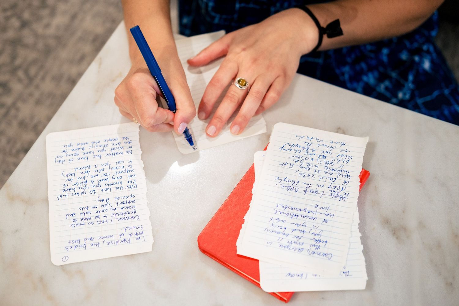 Close-up of handwritten wedding vows on paper cards spread across a marble table surface.