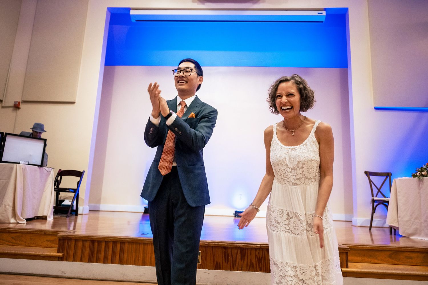 Bride and groom clap and laugh joyfully together after completing their first dance performance.