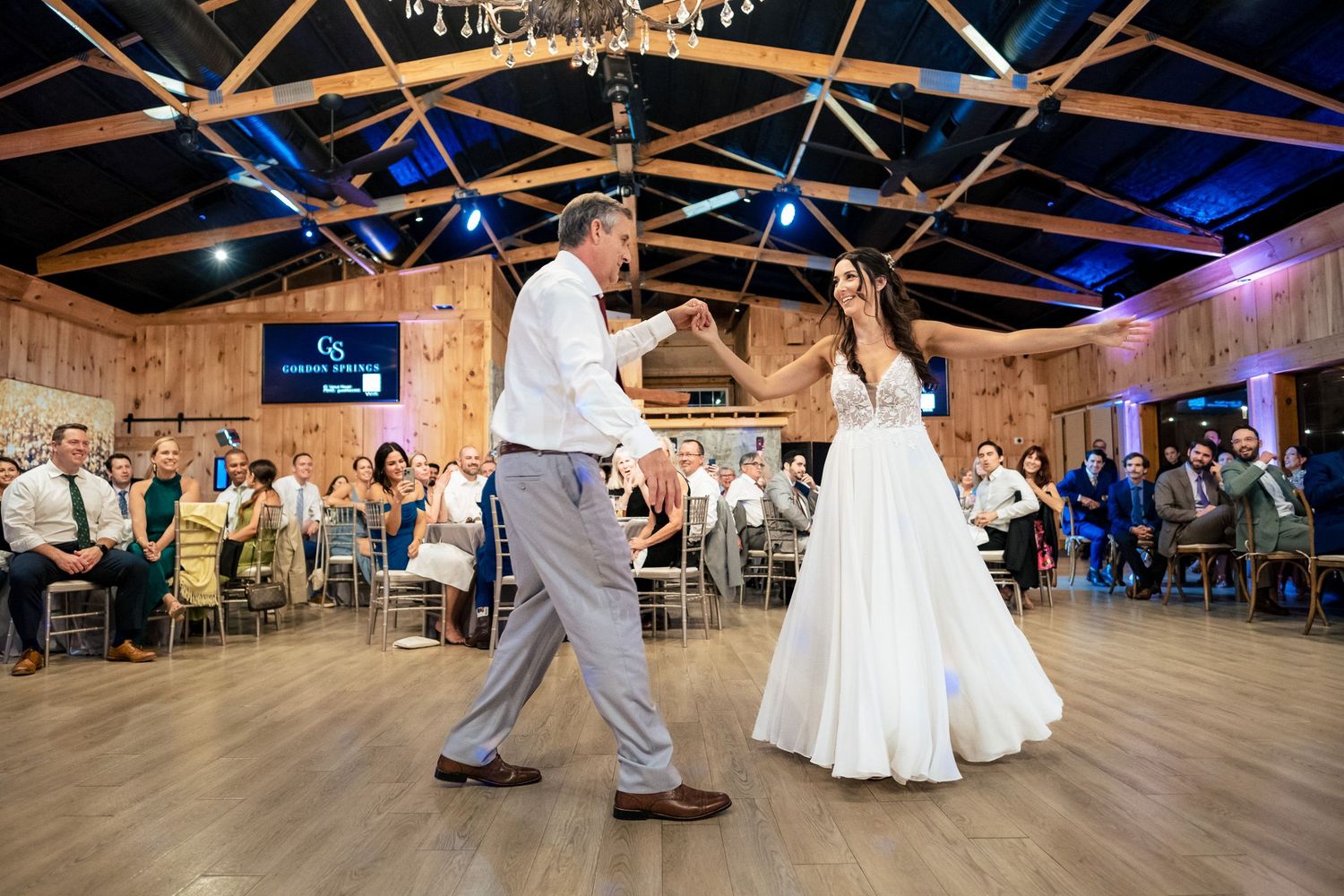 Bride and groom dancing together at rustic barn wedding reception with guests.