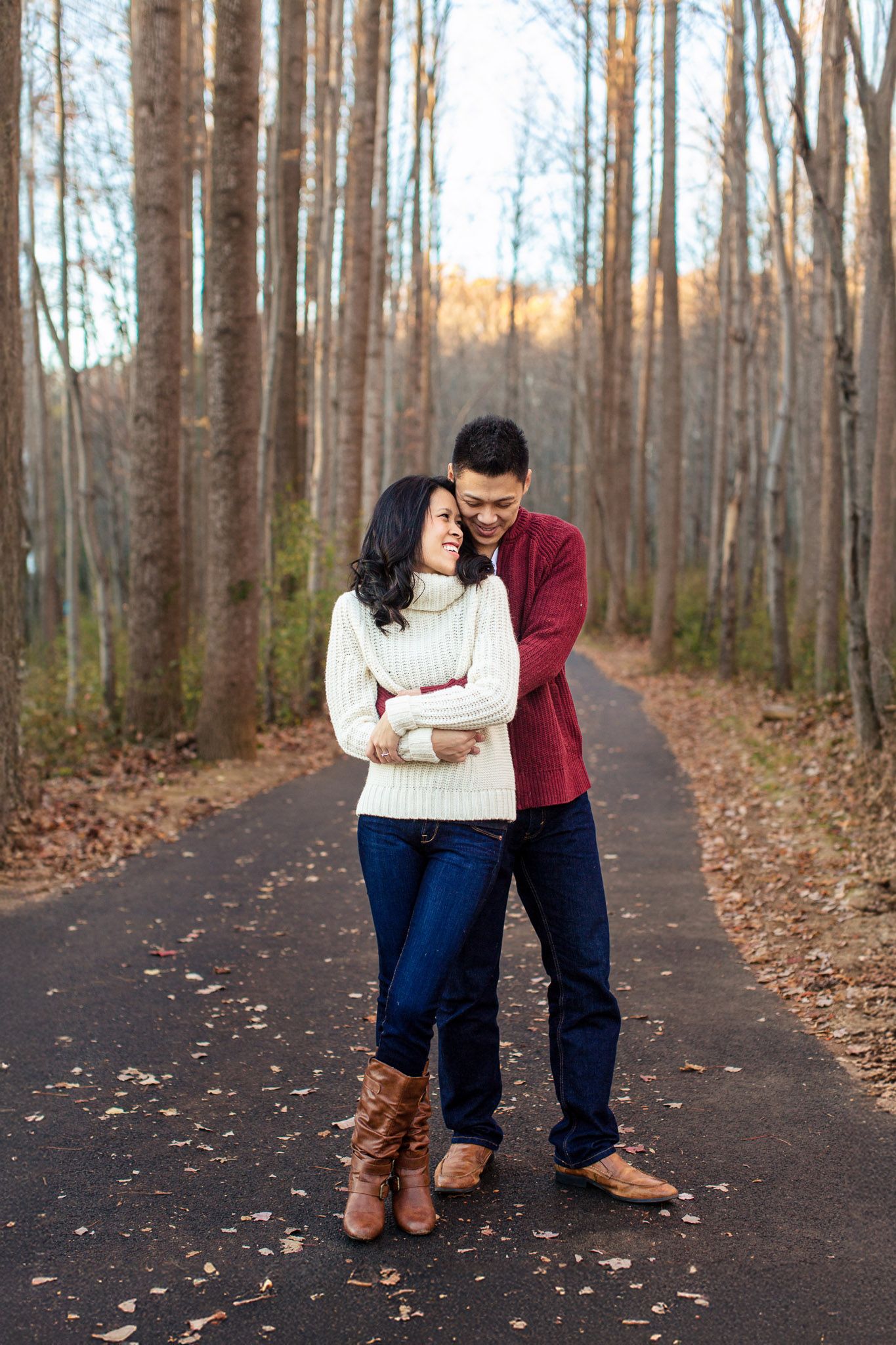 Happy couple embraces warmly on a tree-lined path in autumn forest.