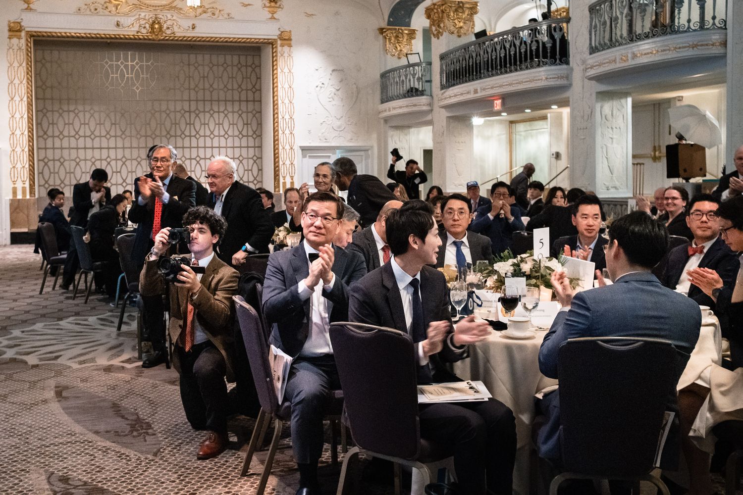 Guests applauding at a formal banquet dinner event in an elegant ballroom venue.
