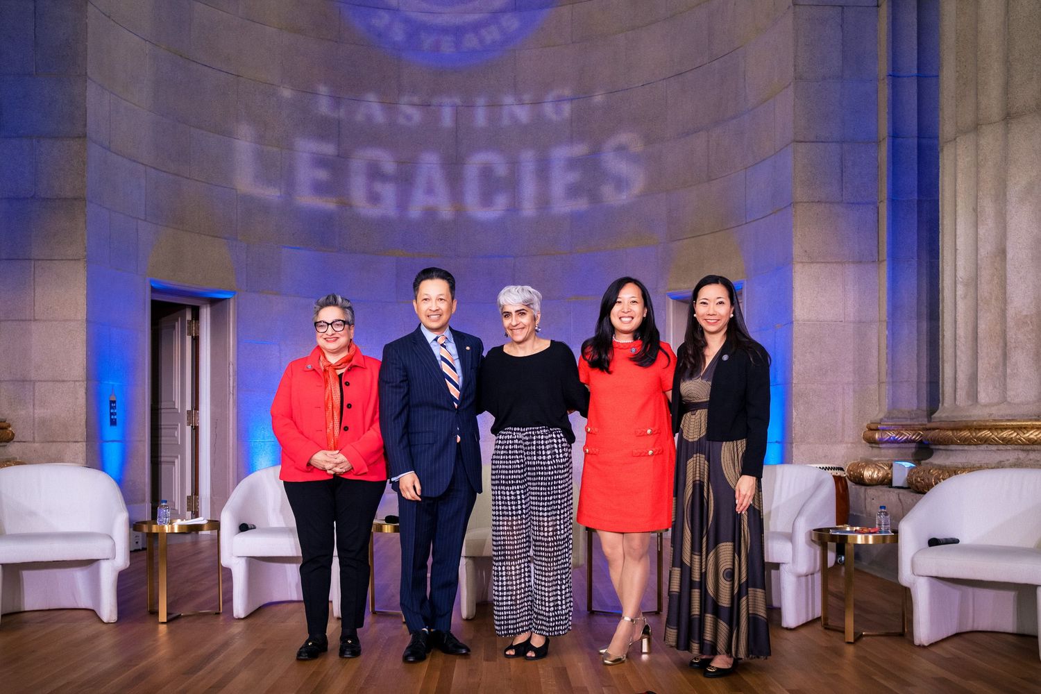 Five professionals pose together at a Lasting Legacies awards event, standing before an elegant illuminated backdrop.