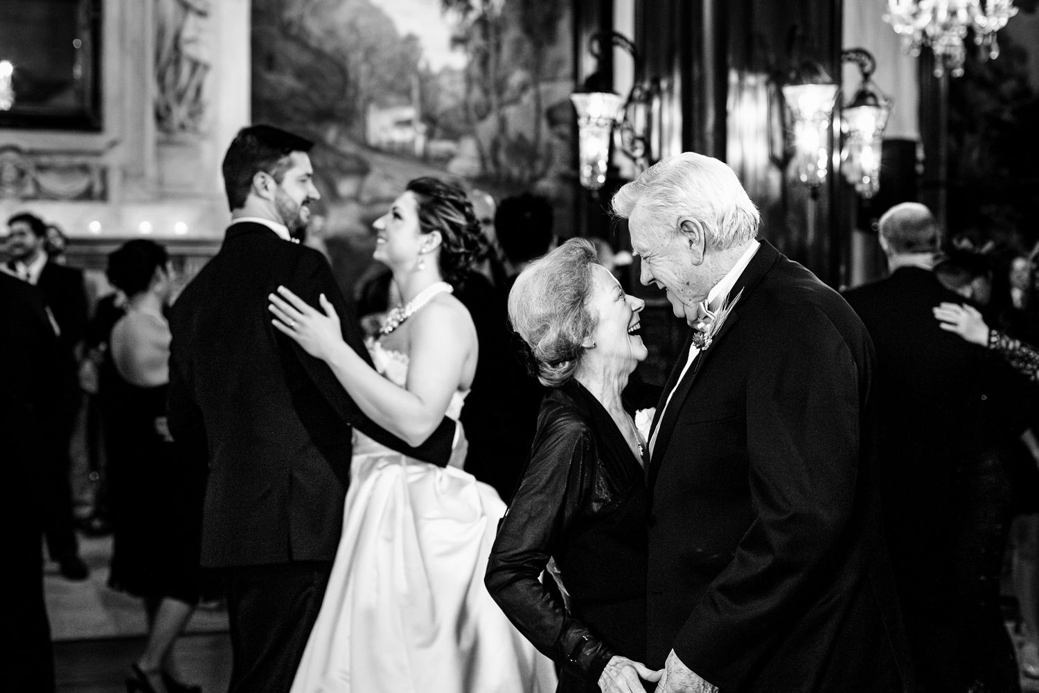 Couples share an elegant moment dancing and greeting guests at a black and white formal wedding reception.
