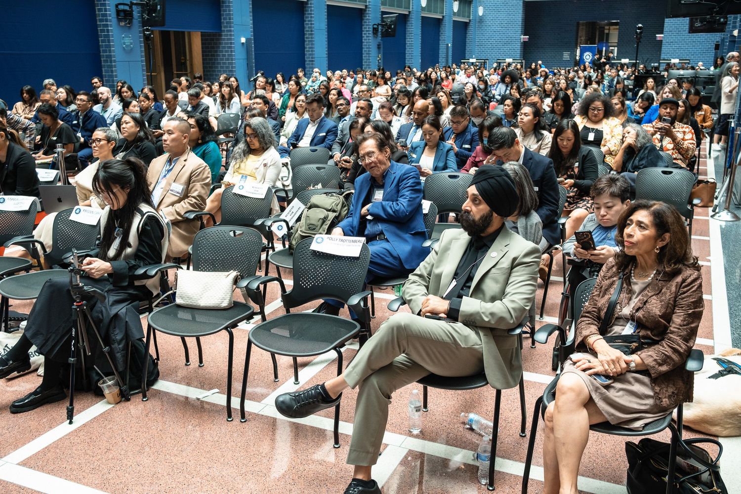 A diverse audience fills rows of chairs at a professional conference or seminar event.