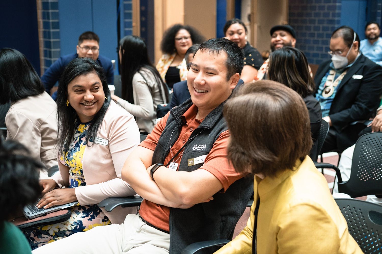 Diverse group of professionals networking and smiling at a business event, engaged in friendly conversation.