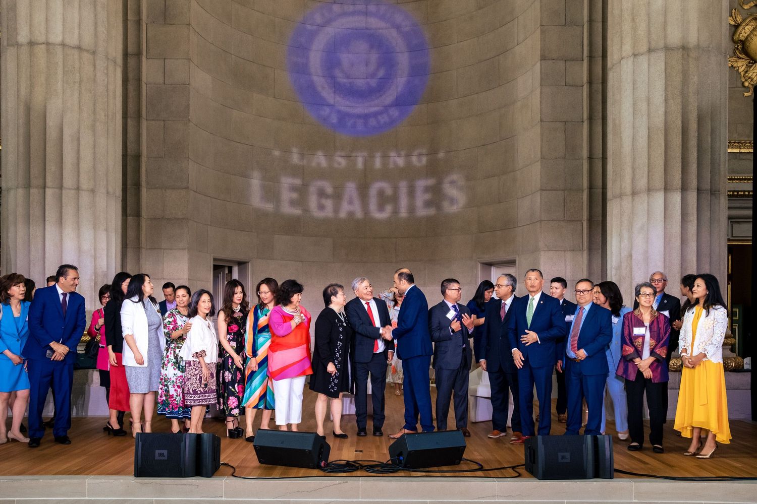 Group of diverse professionals gathered at a Lasting Legacies award ceremony in an elegant government building.