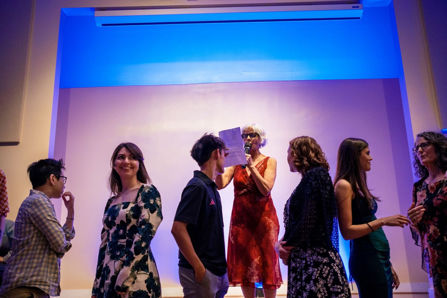 Wedding guests mingle and socialize under blue ambient lighting at an indoor reception venue.