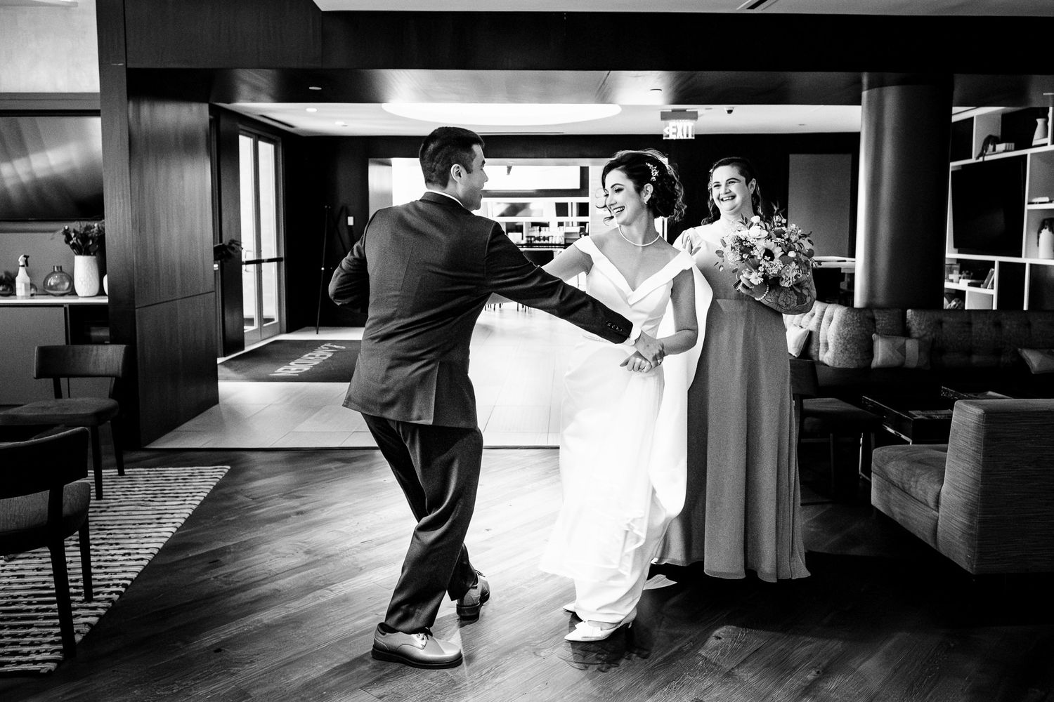 Groom reacts with joy as bride arrives holding bouquet during indoor black and white first look moment.