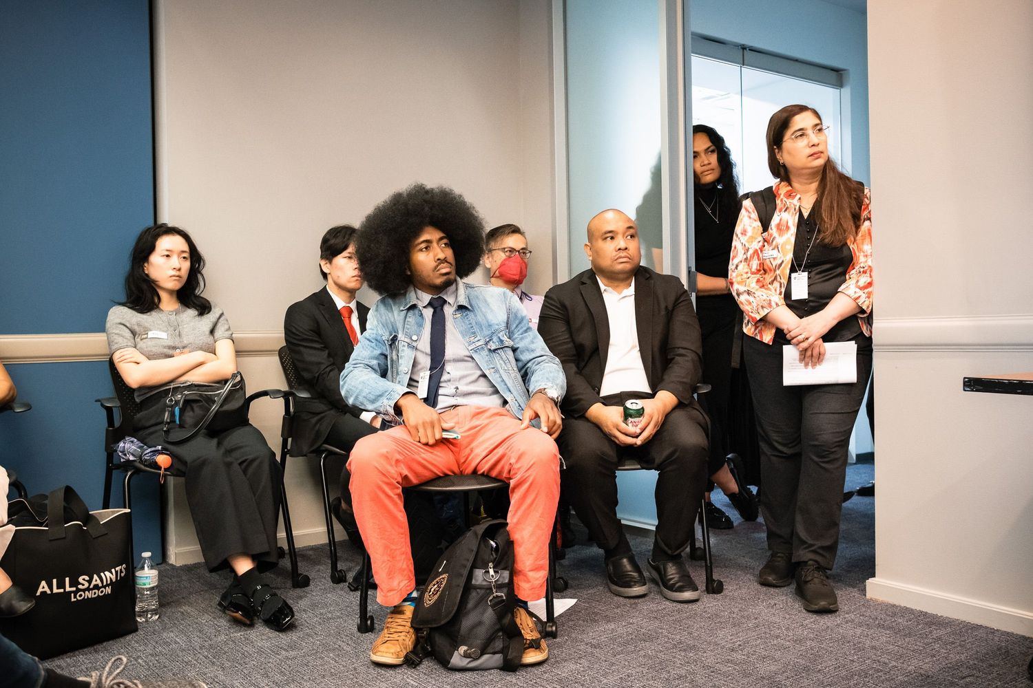 Diverse group of attendees listening attentively during a professional conference session in a modern meeting room.