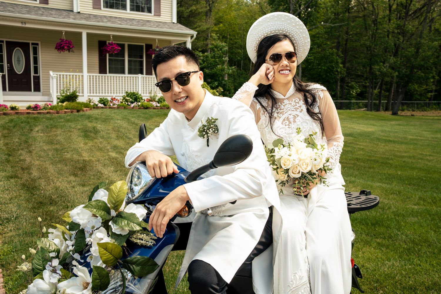 Vietnamese wedding couple pose on a scooter in traditional white ao dai attire outdoors.