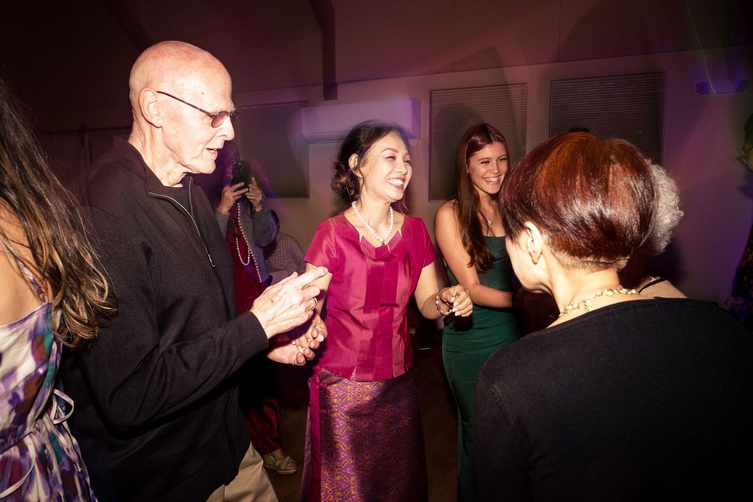 Guests in elegant attire socialize and laugh together at a wedding reception party.
