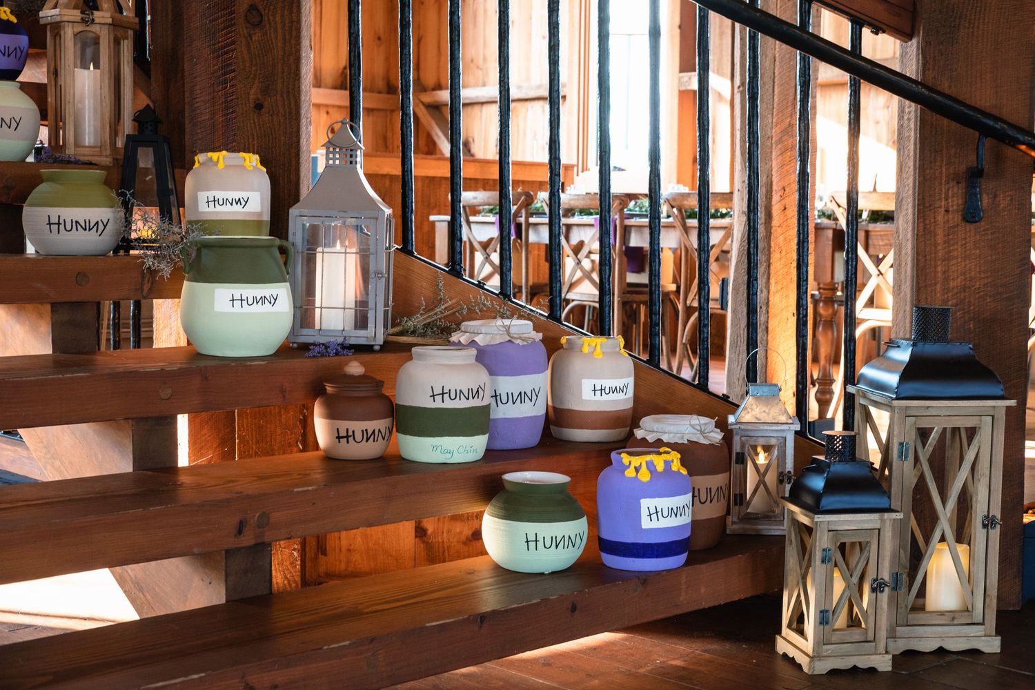 Colorful Hunny pot centerpieces and lanterns displayed on wooden stairs at Winnie the Pooh wedding.