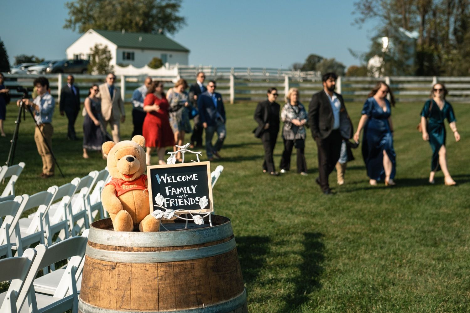 Tigger stuffed animal and welcome sign on a barrel greet guests at an outdoor wedding ceremony.