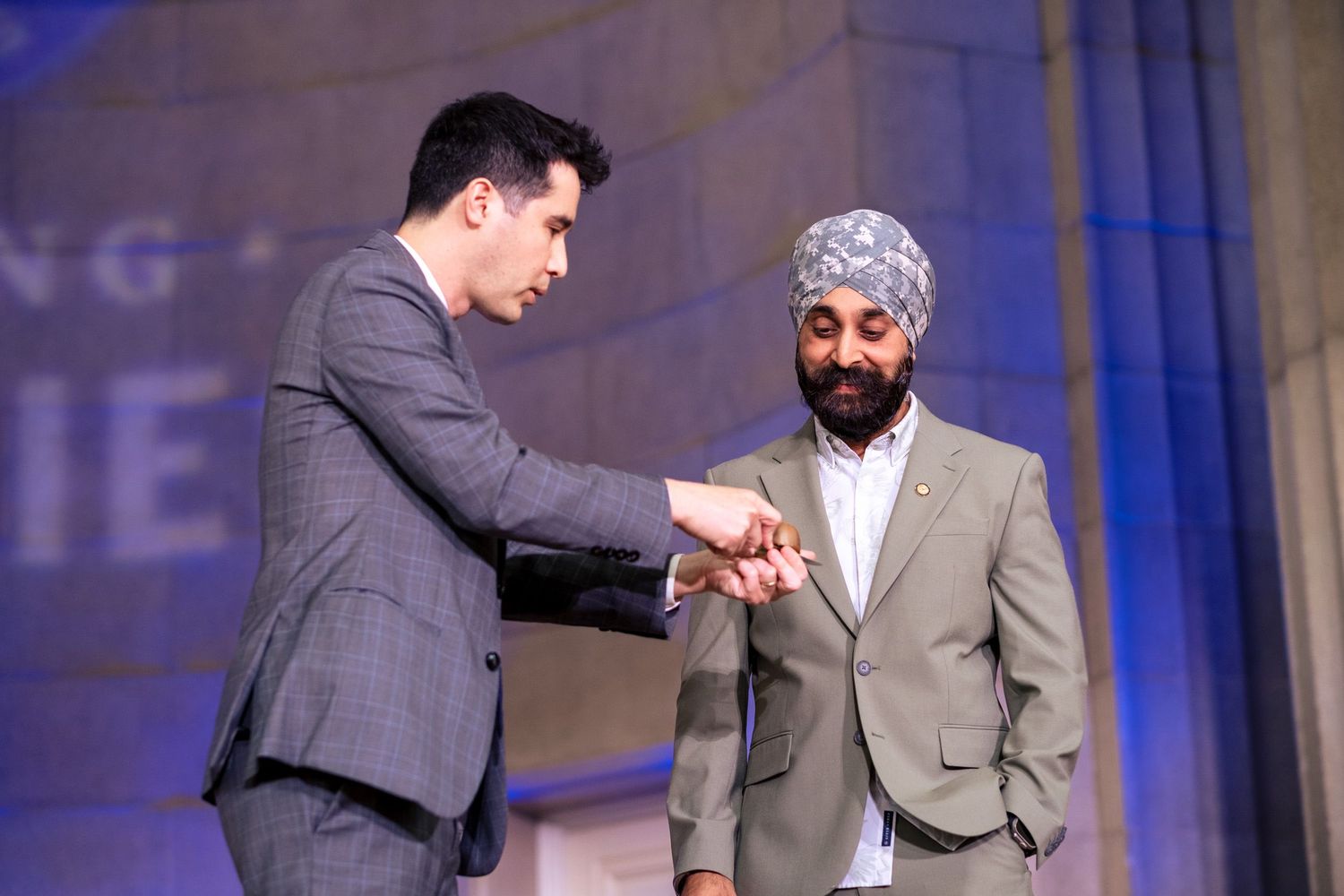 Two men in suits shake hands on stage at a formal awards ceremony event.