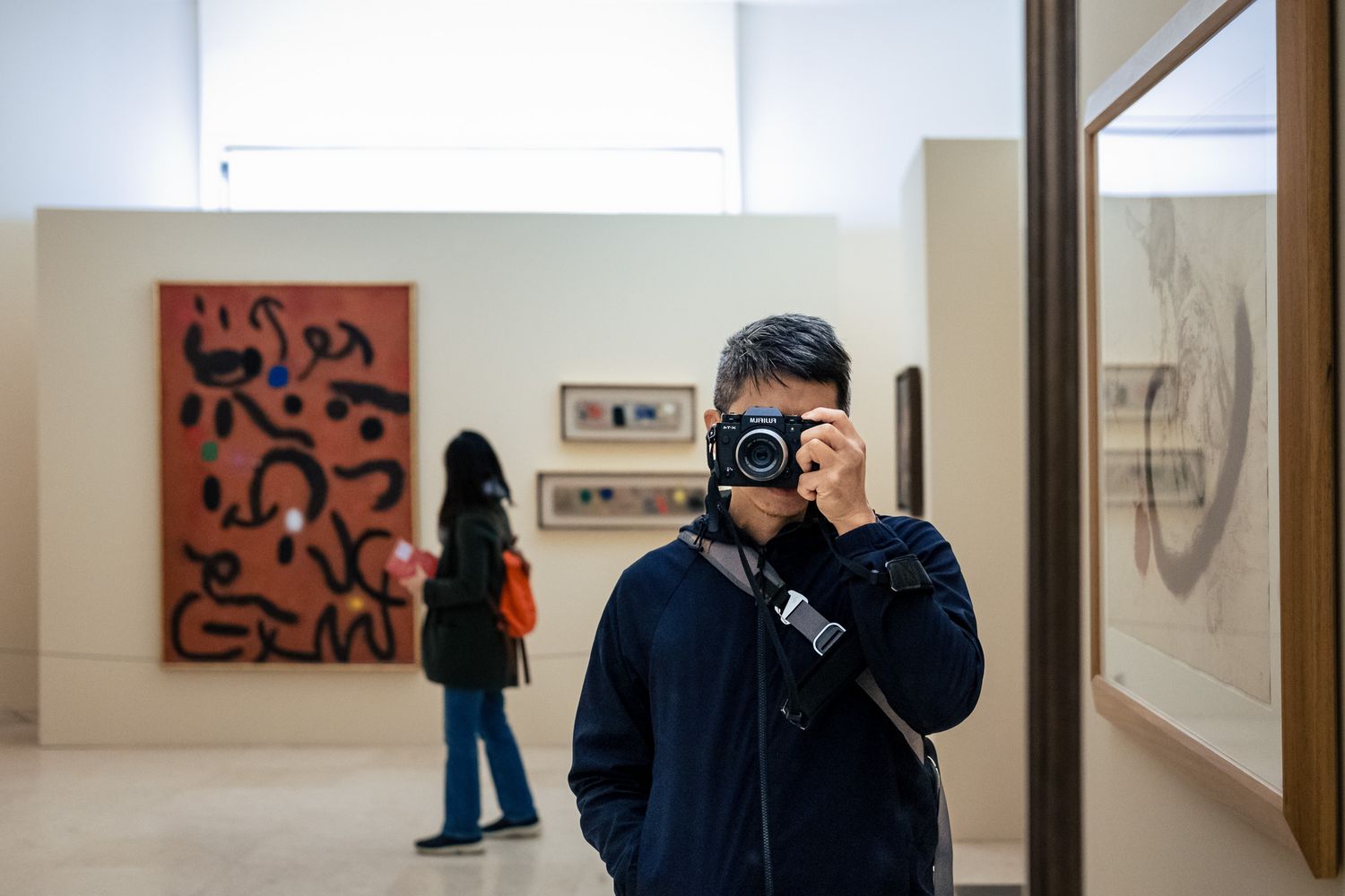 James captures selfie and artwork with a camera inside a bright modern art museum gallery.