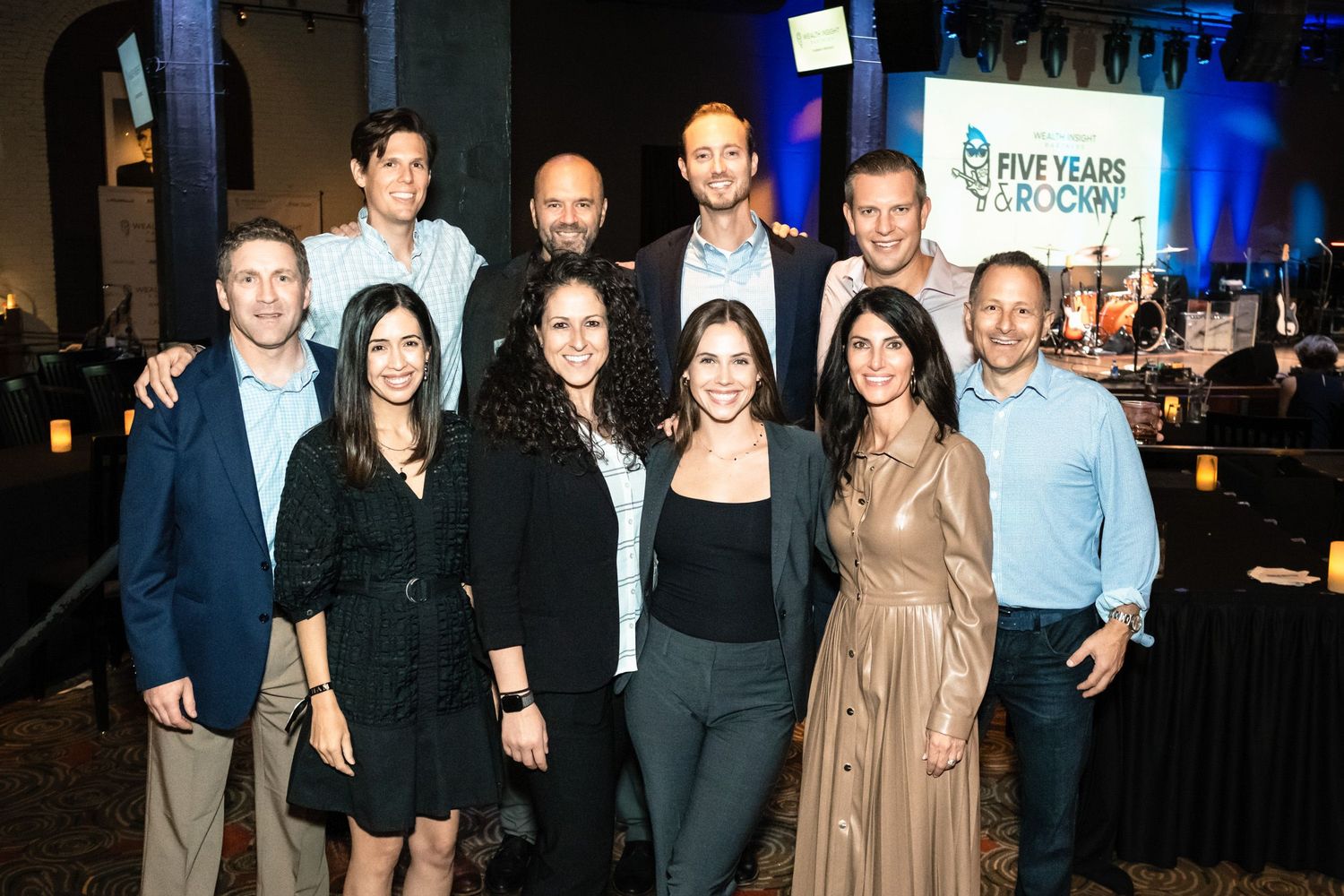 Group of professionals posing together at a Five Years & Roomy anniversary gala event in an elegant venue.