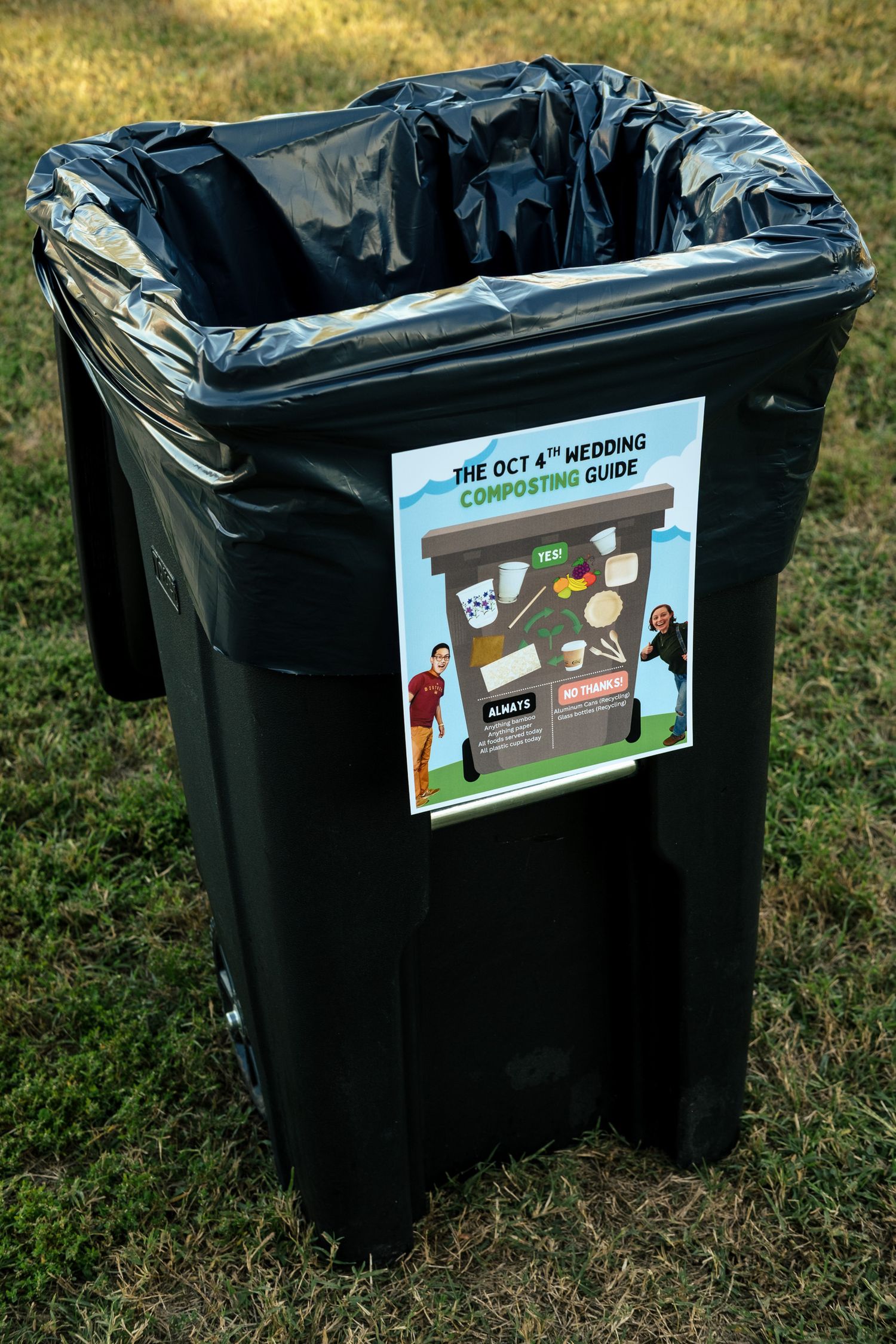 Black compost bin with an Oct 4th wedding composting guide sign attached, on grass.