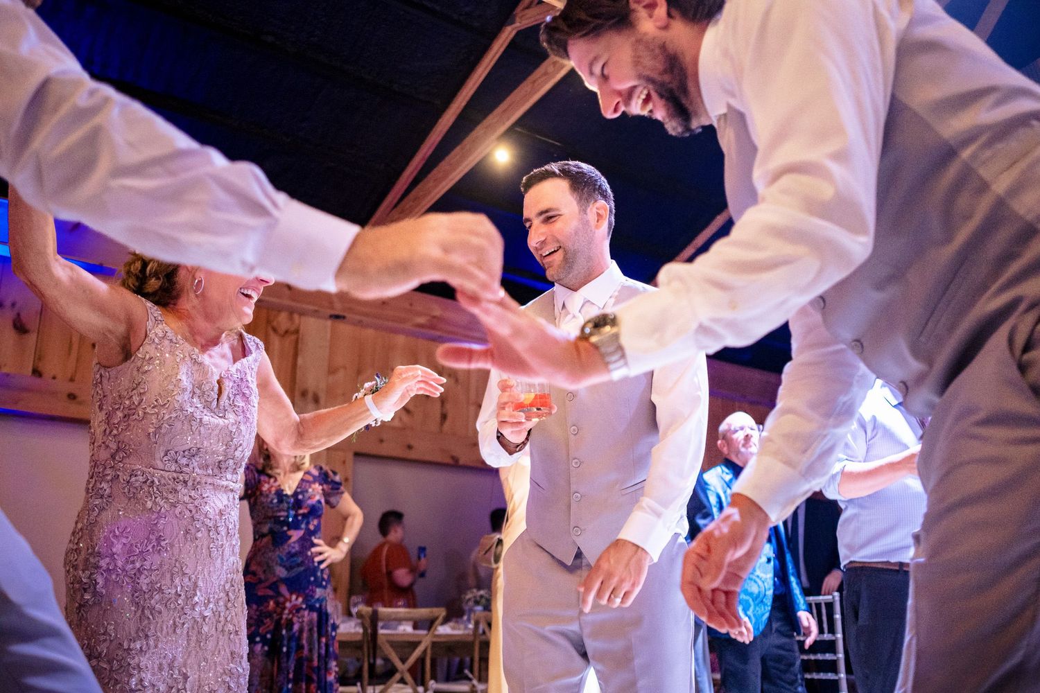 Groom dancing energetically with guests at lively wedding reception celebration.
