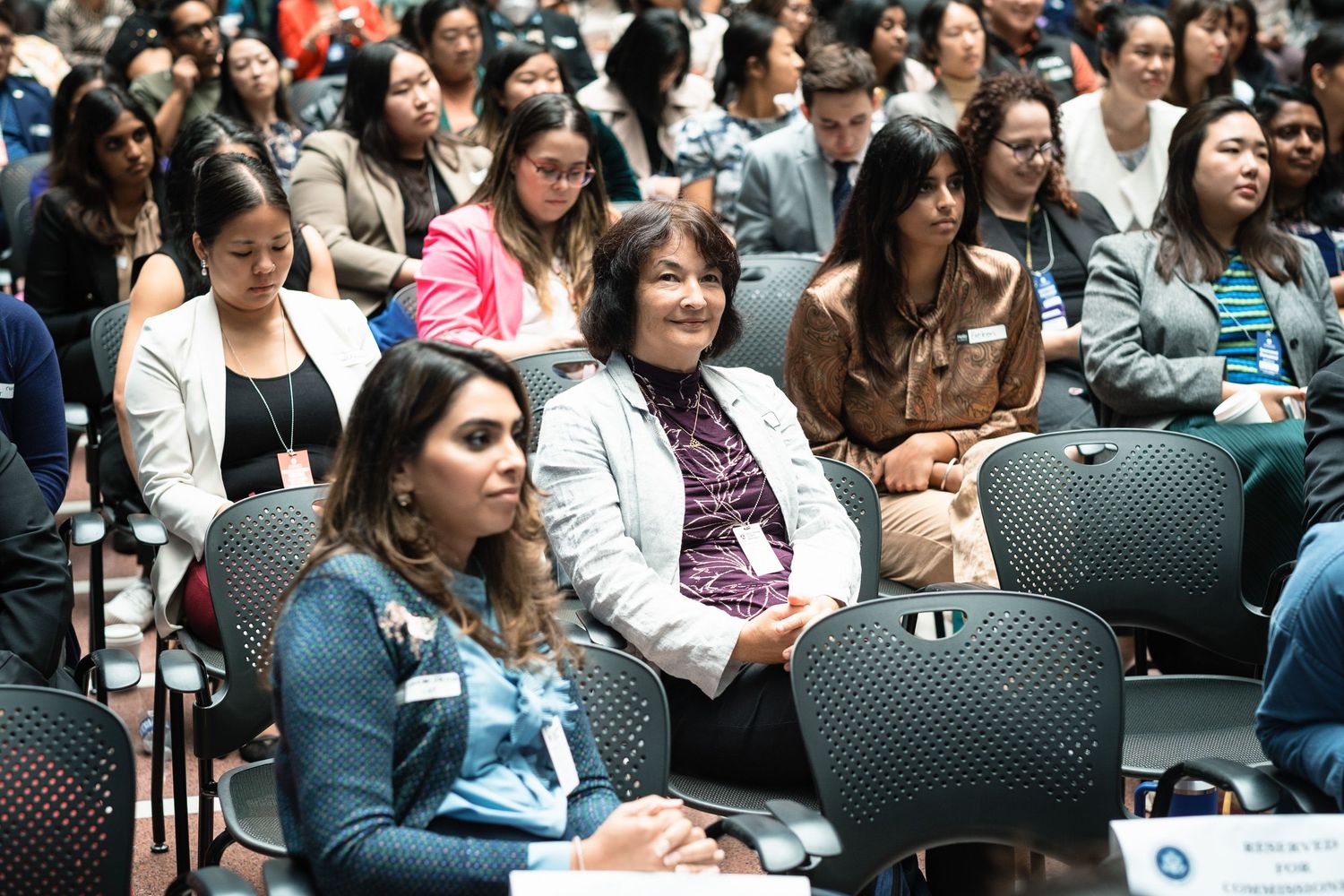 Diverse group of women attendees engaged and smiling at a professional conference or seminar event.