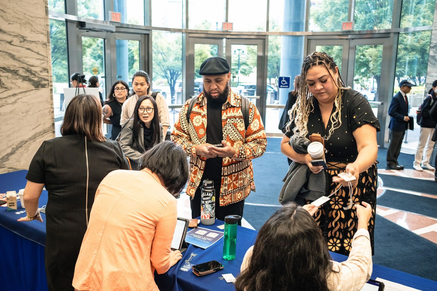 Professionals networking at a conference registration table in a modern building lobby.