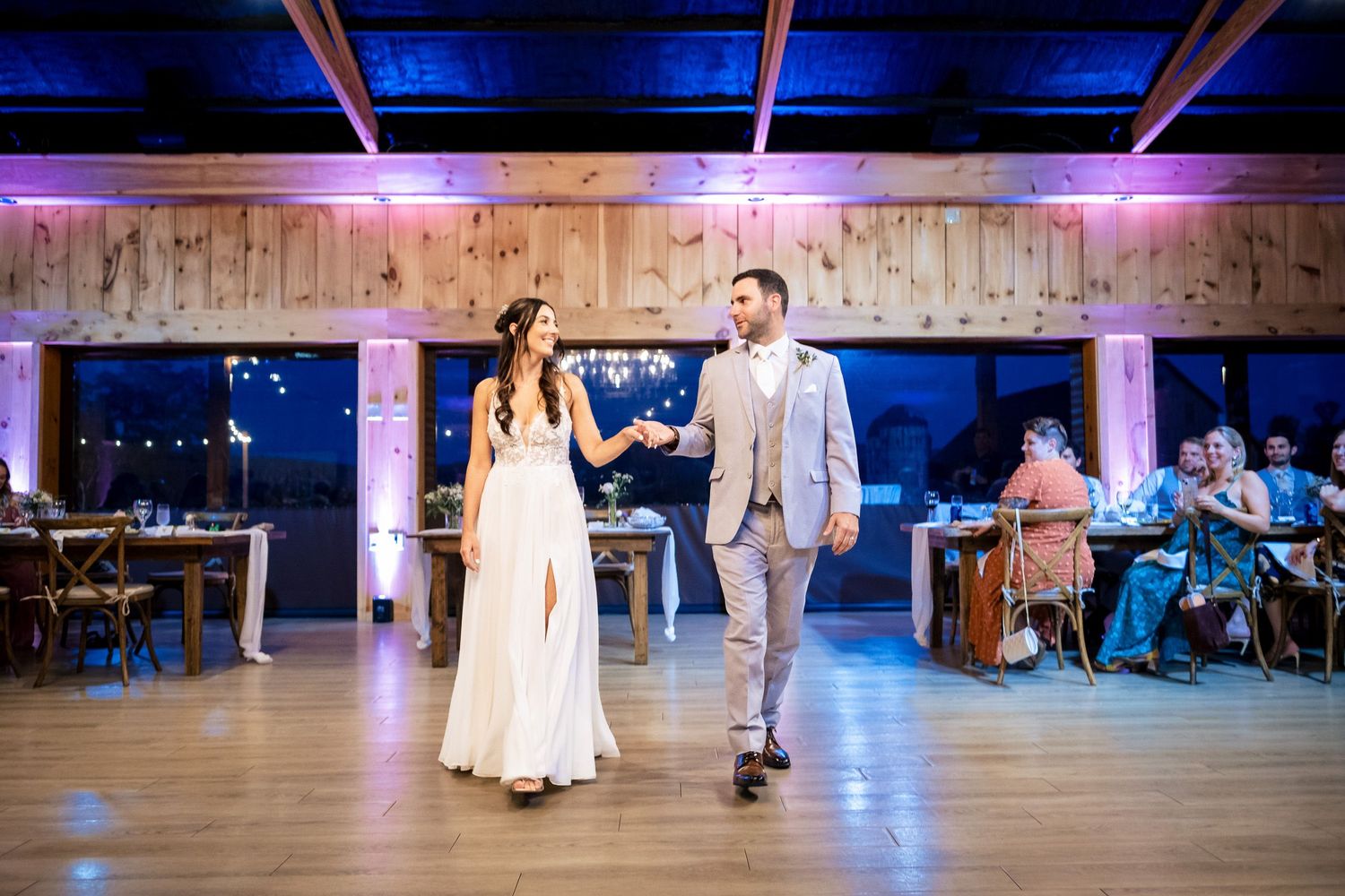 Bride and groom share their first dance under blue uplighting in a rustic barn wedding venue.