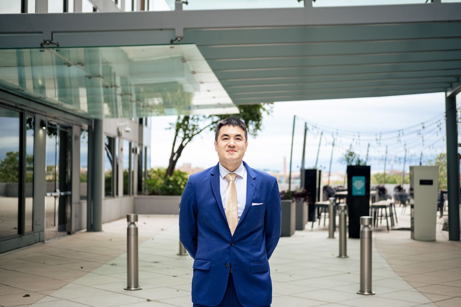 Groom in royal blue suit stands confidently outside modern venue entrance on wedding day.
