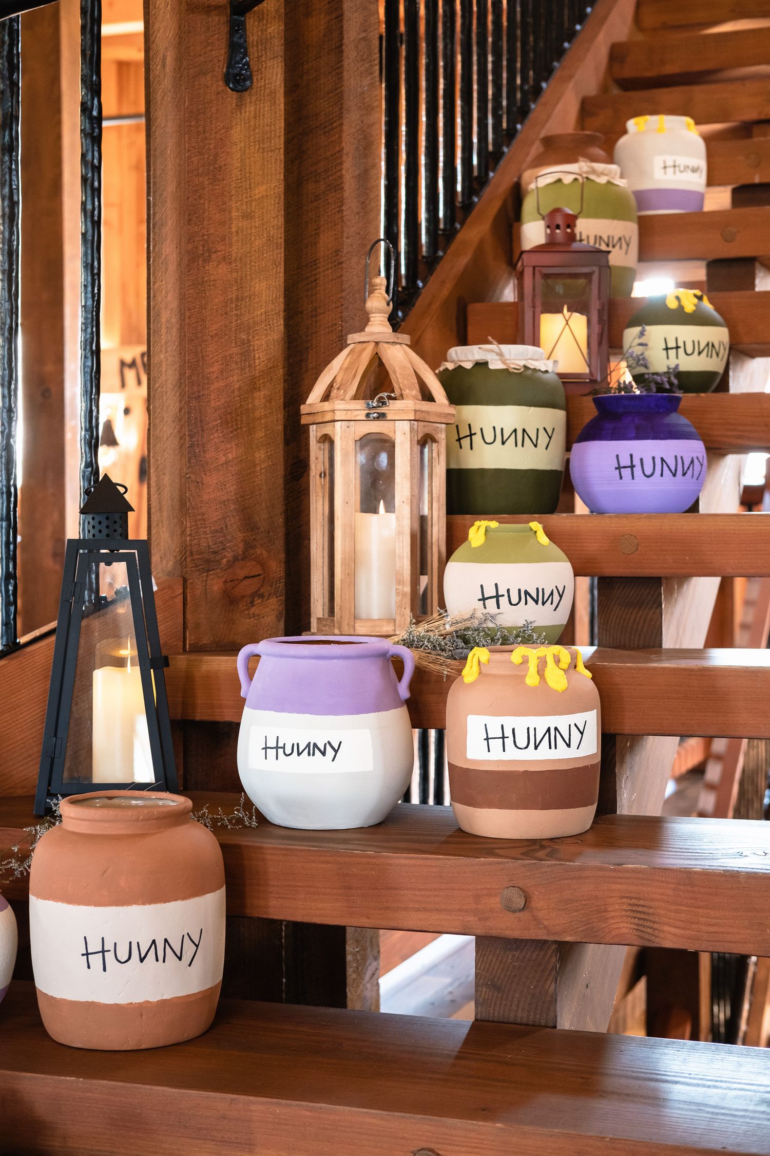 Colorful Hunny pots inspired by Winnie the Pooh decorate wooden stairs at a wedding venue.