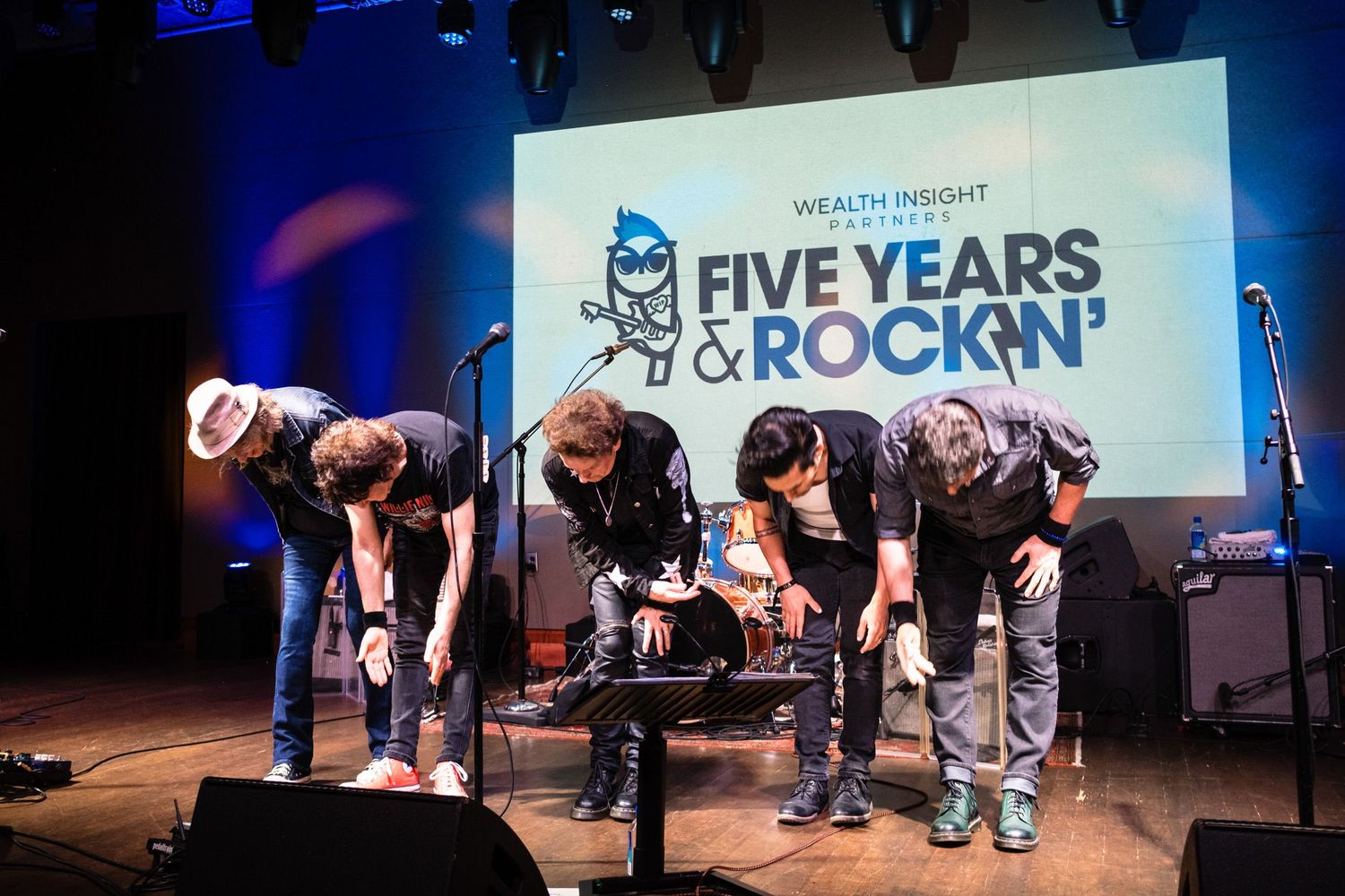 Four performers bow on stage at Wealth Insight Partners Five Years & Rockin' anniversary celebration event.