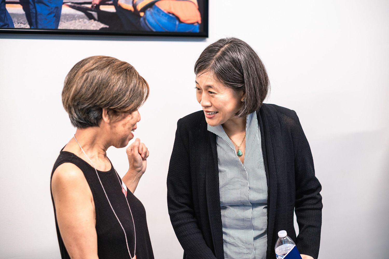 Two women engaged in conversation at an art gallery or professional networking event.