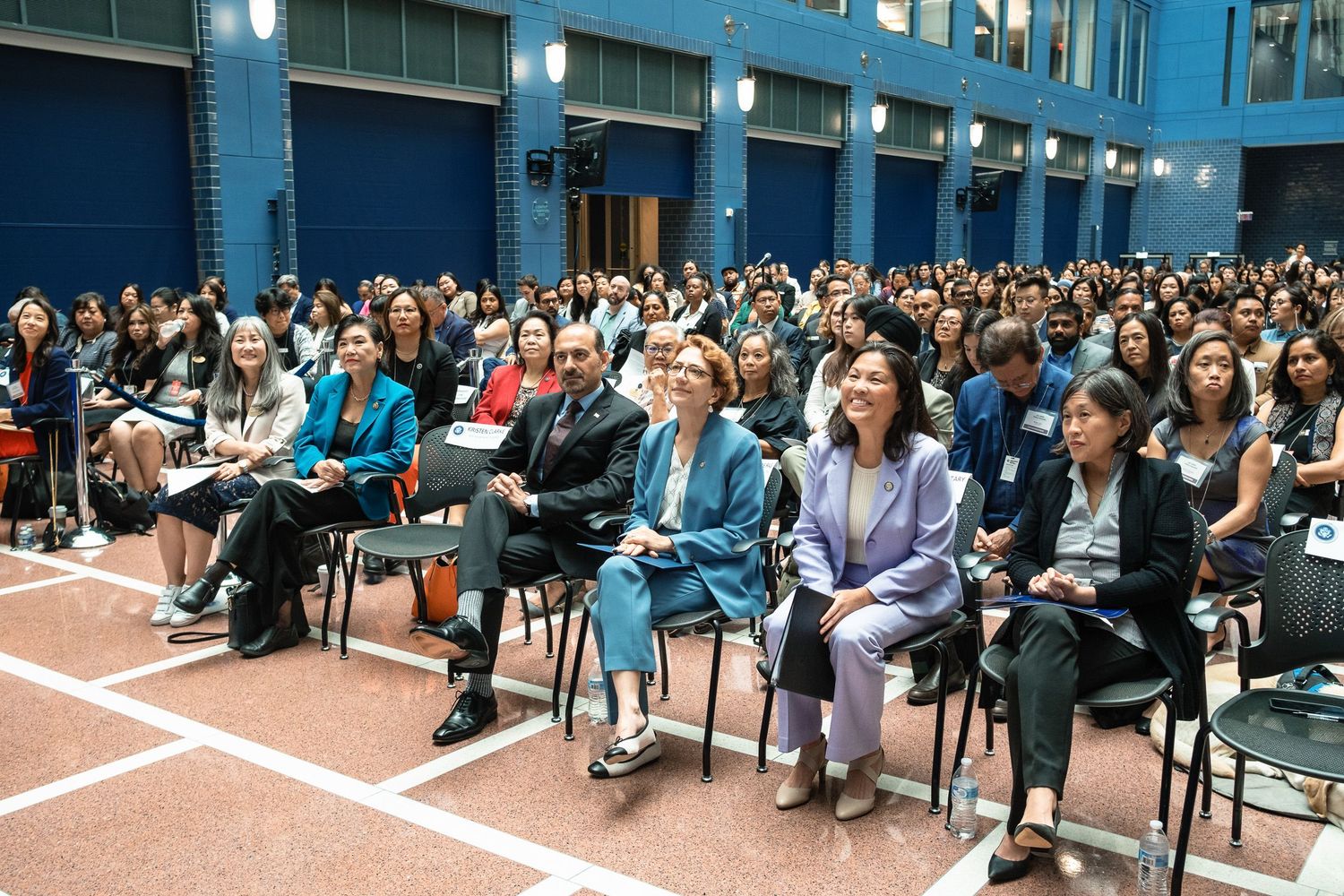 Large audience of diverse professionals seated in rows at an indoor conference or seminar event.