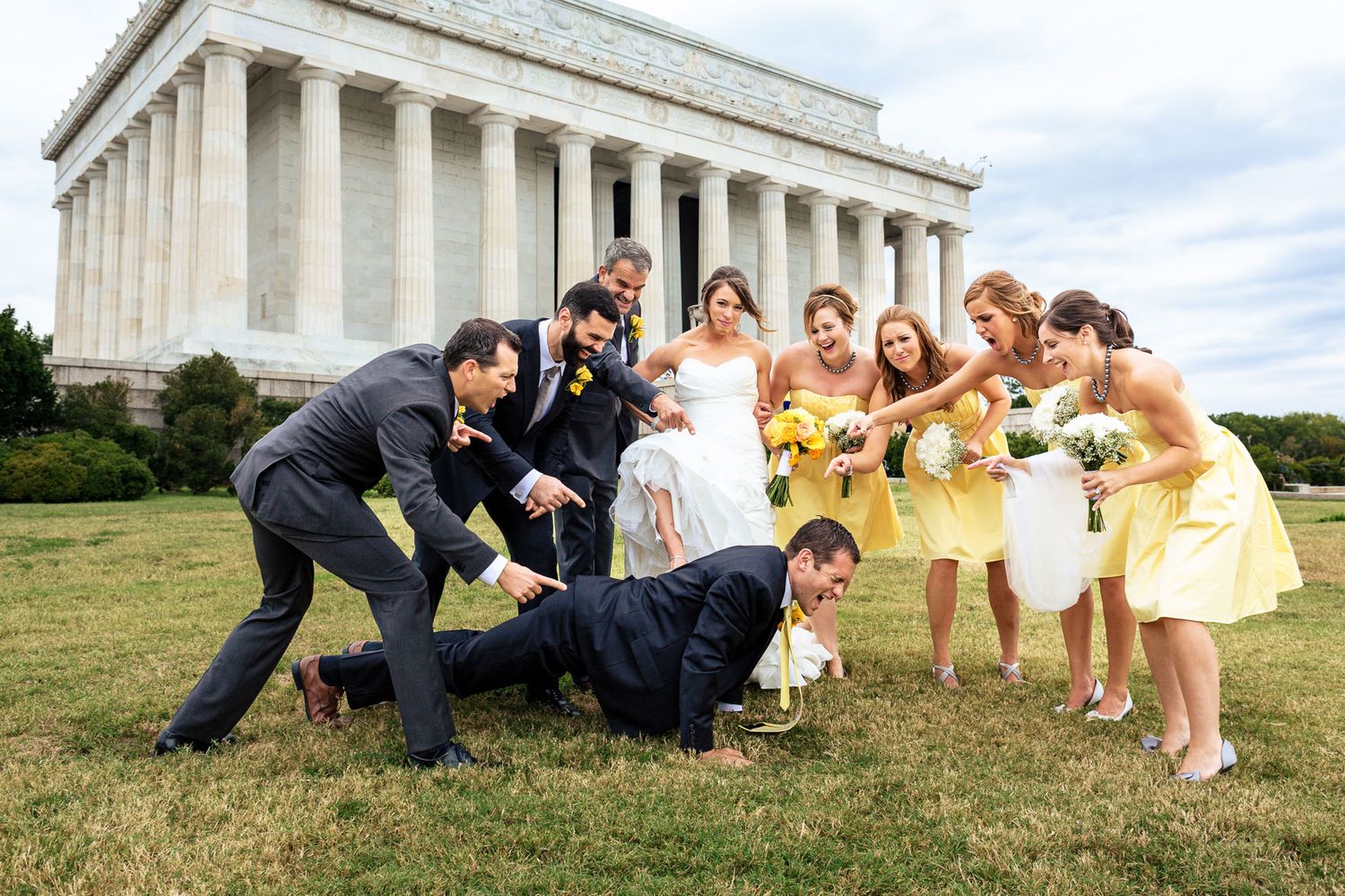 Wedding party posing playfully on the lawn in front of the Lincoln Memorial.