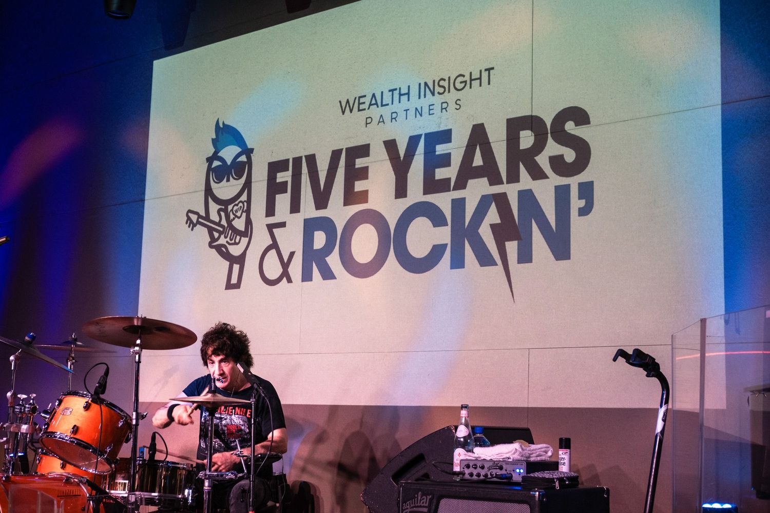 Drummer performing on stage at Wealth Insight Partners Five Years & Rockin' anniversary celebration event.