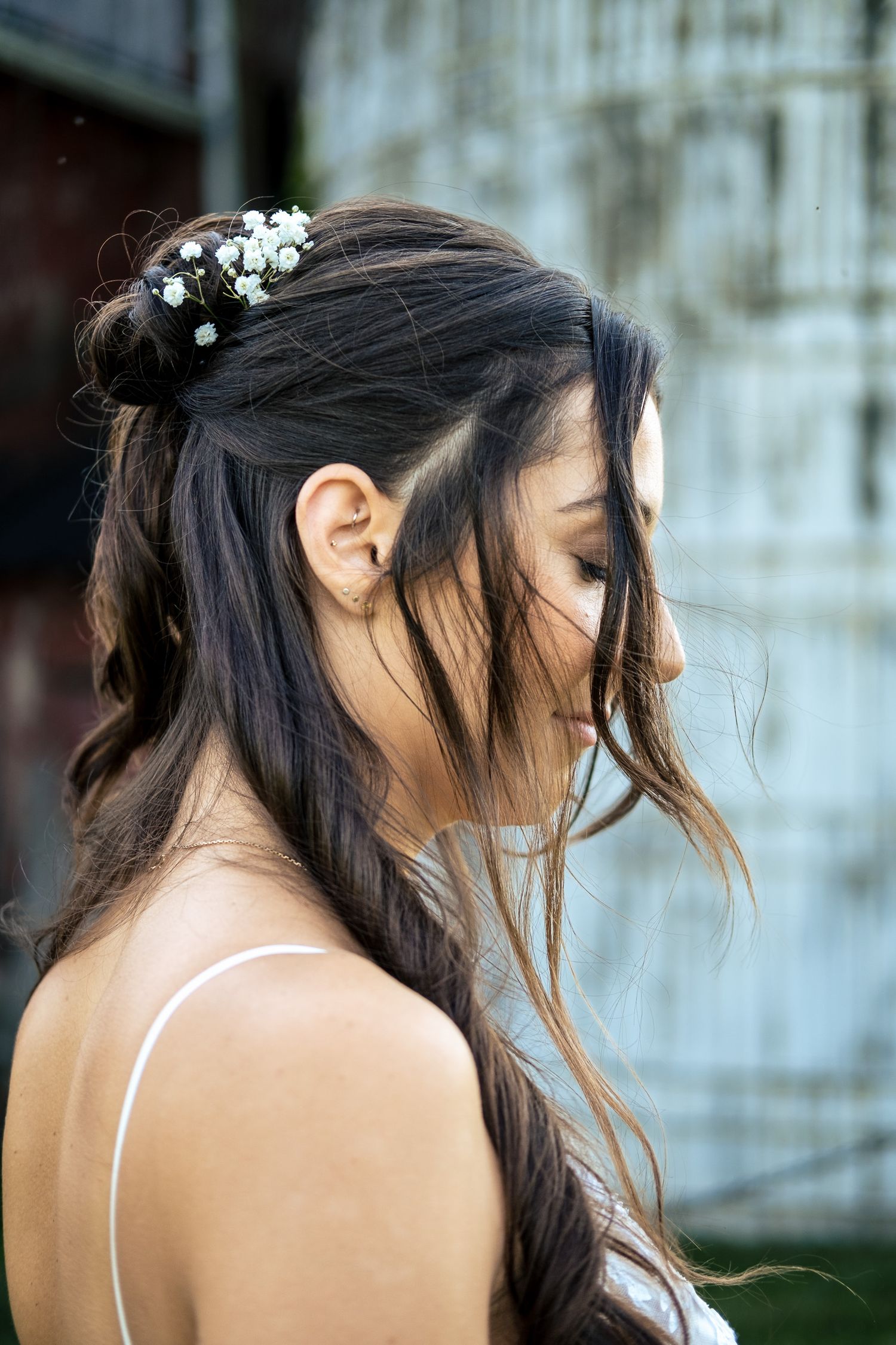 Close-up of bride with half-up hairstyle adorned with small white flowers at a barn wedding.
