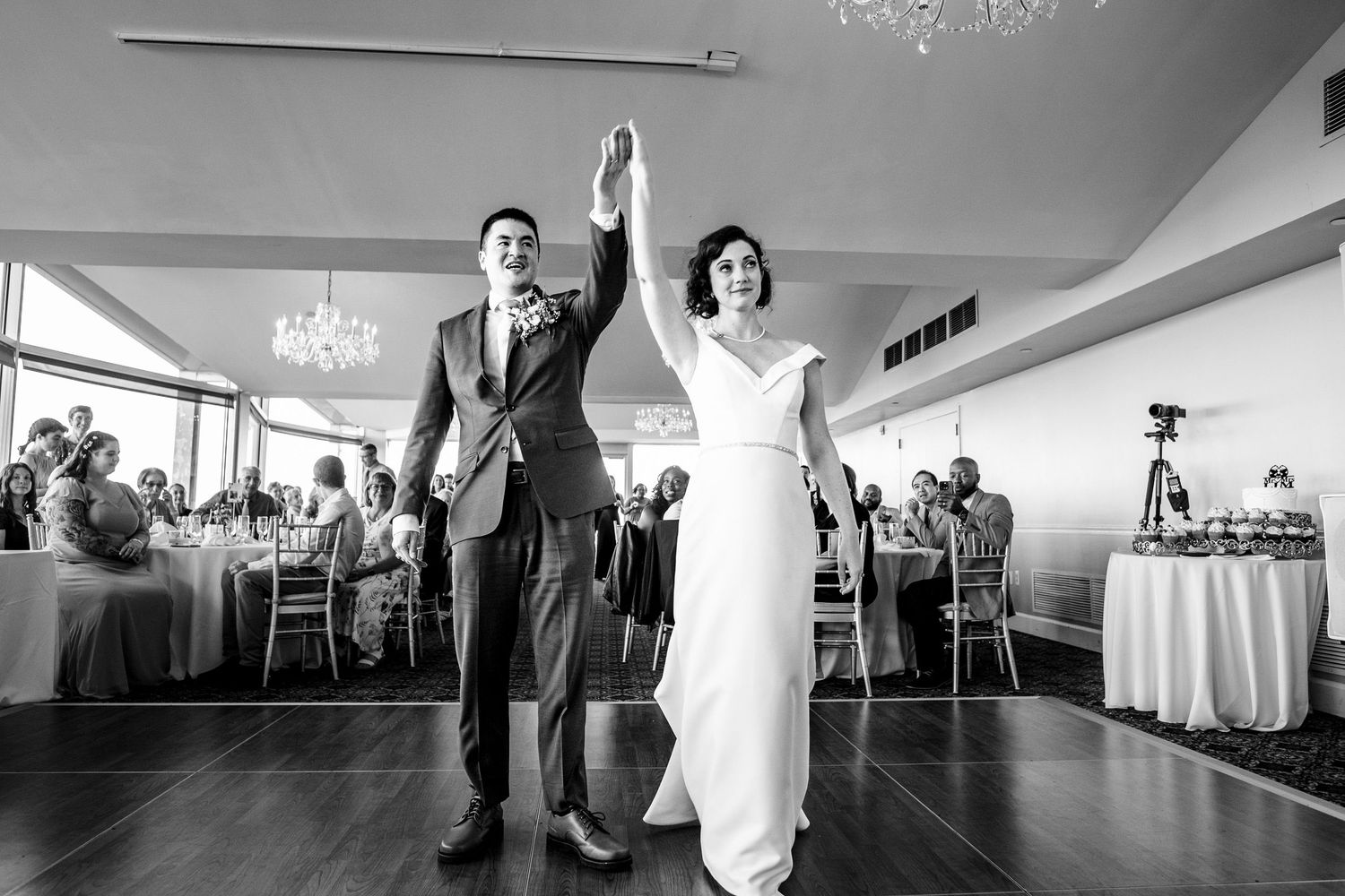 Bride and groom raising hands as they enter their wedding reception ballroom.