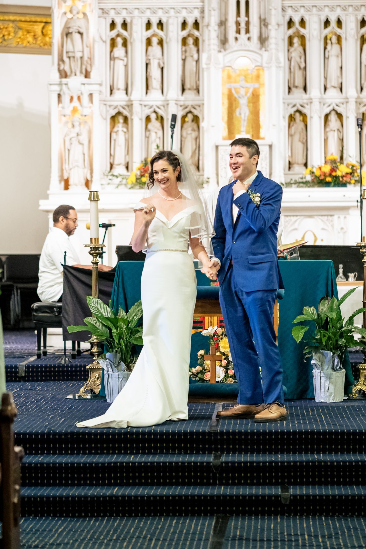 Bride and groom celebrate joyfully at the altar after being pronounced married in a church ceremony.