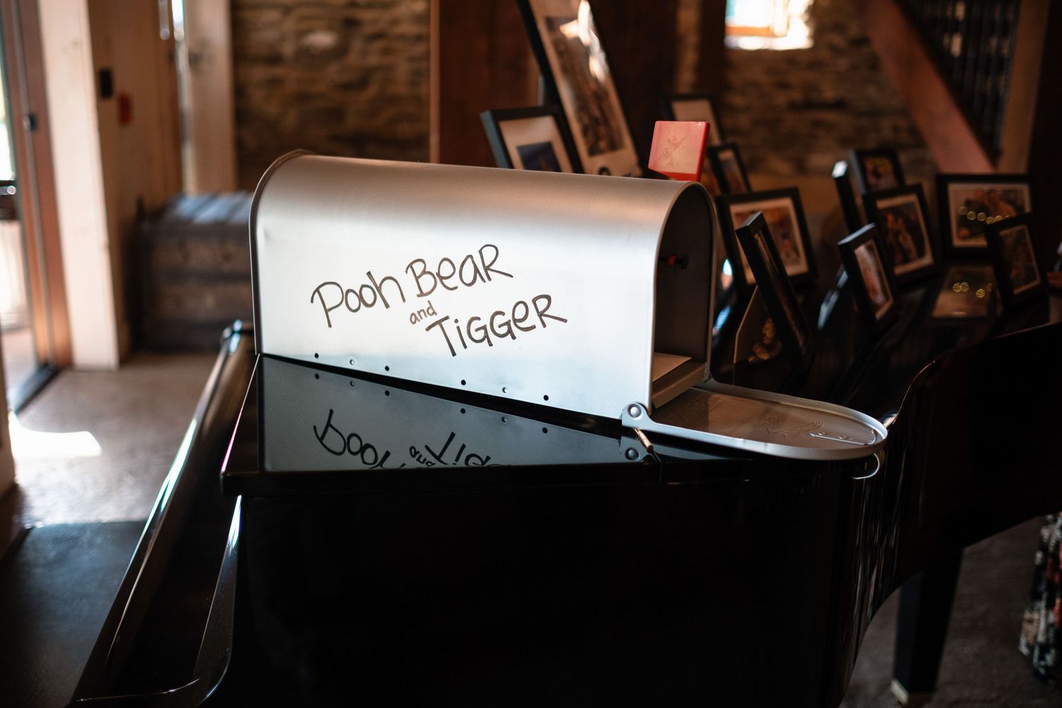 Wedding mailbox labeled Pooh Bear and Tigger used as card holder at rustic barn reception.