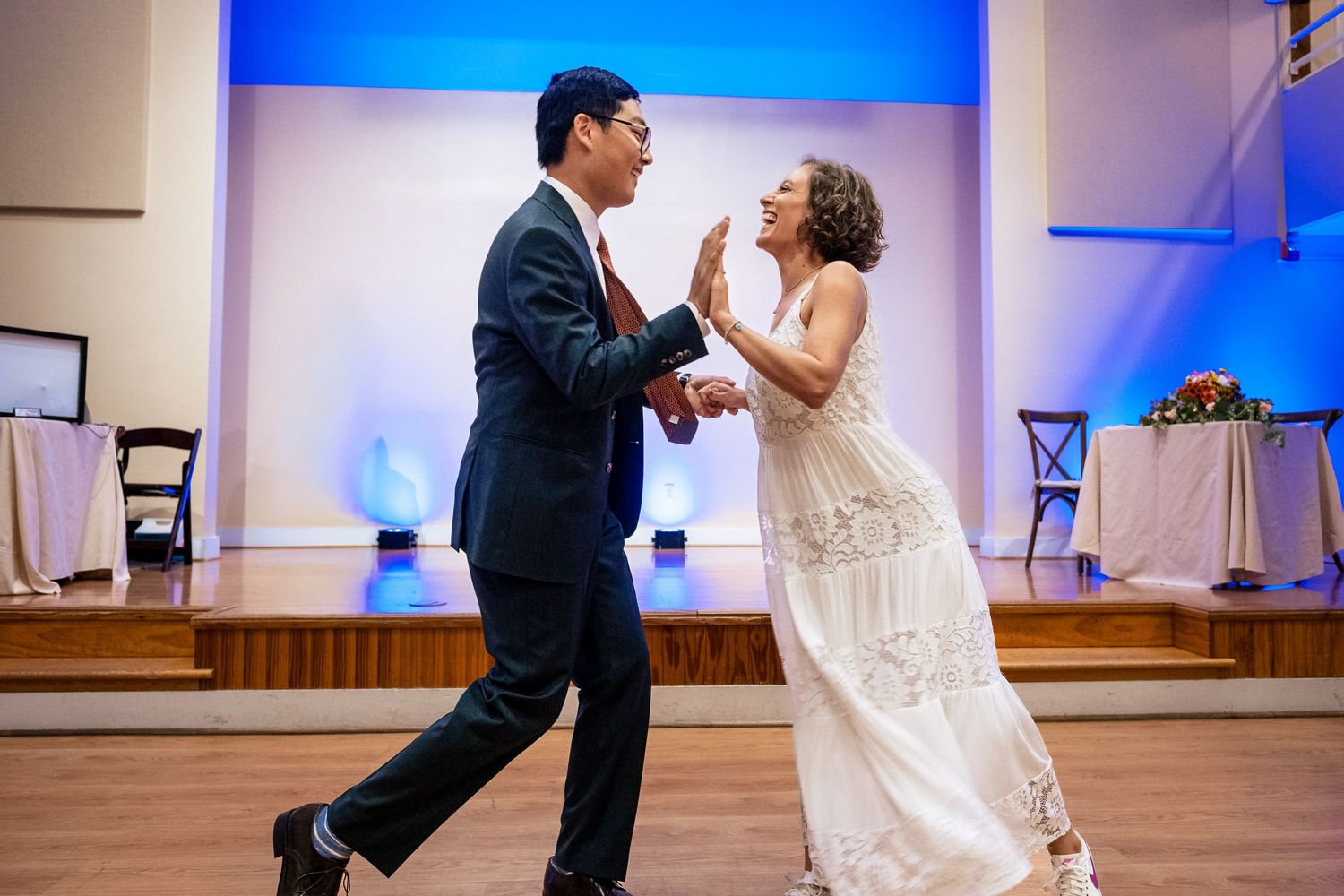 Bride and groom share a playful high-five moment during their first dance at wedding reception.