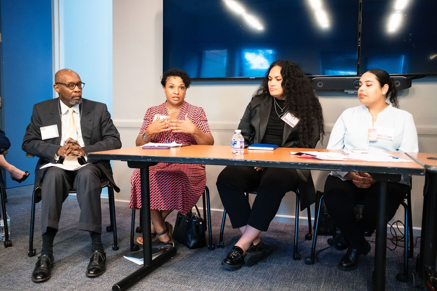 Four professionals seated at a conference table engaged in a panel discussion in a modern meeting room.