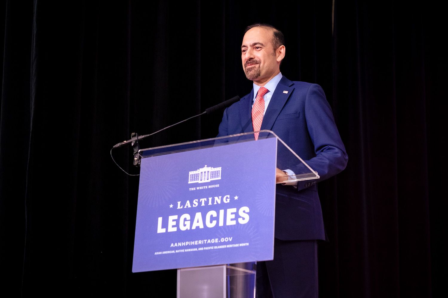 Man in suit speaking at podium during Lasting Legacies event, white house logo visible on lectern.