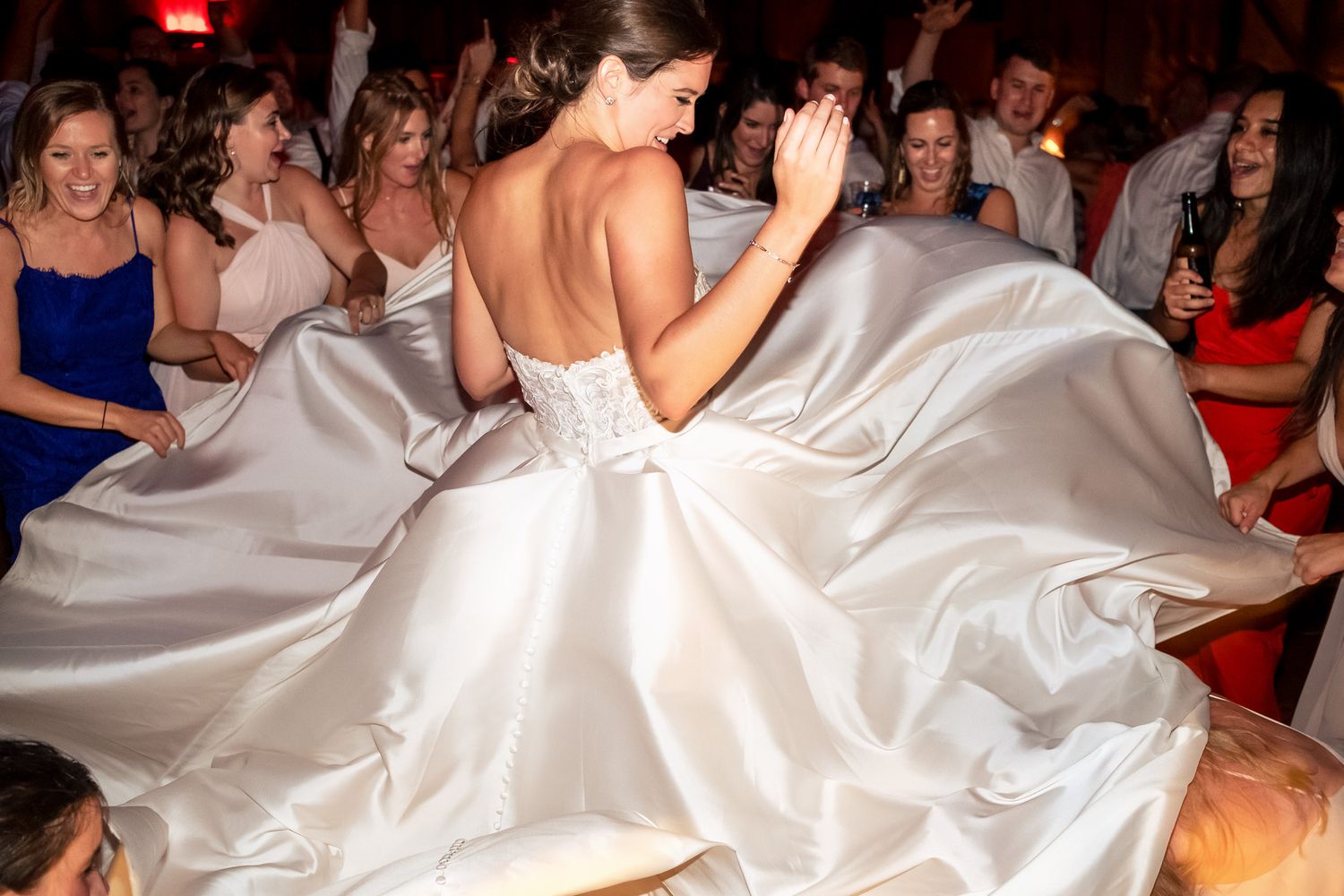 Bride twirling in a stunning strapless ball gown on a crowded wedding reception dance floor.